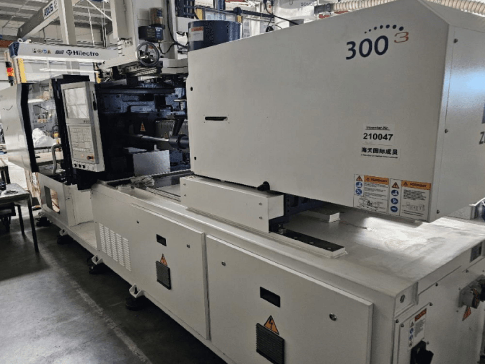 Máquina de moldeo por inyección, marca Zhenjing, modelo 300, vista frontal con panel de control y etiquetas de advertencia de seguridad visibles.