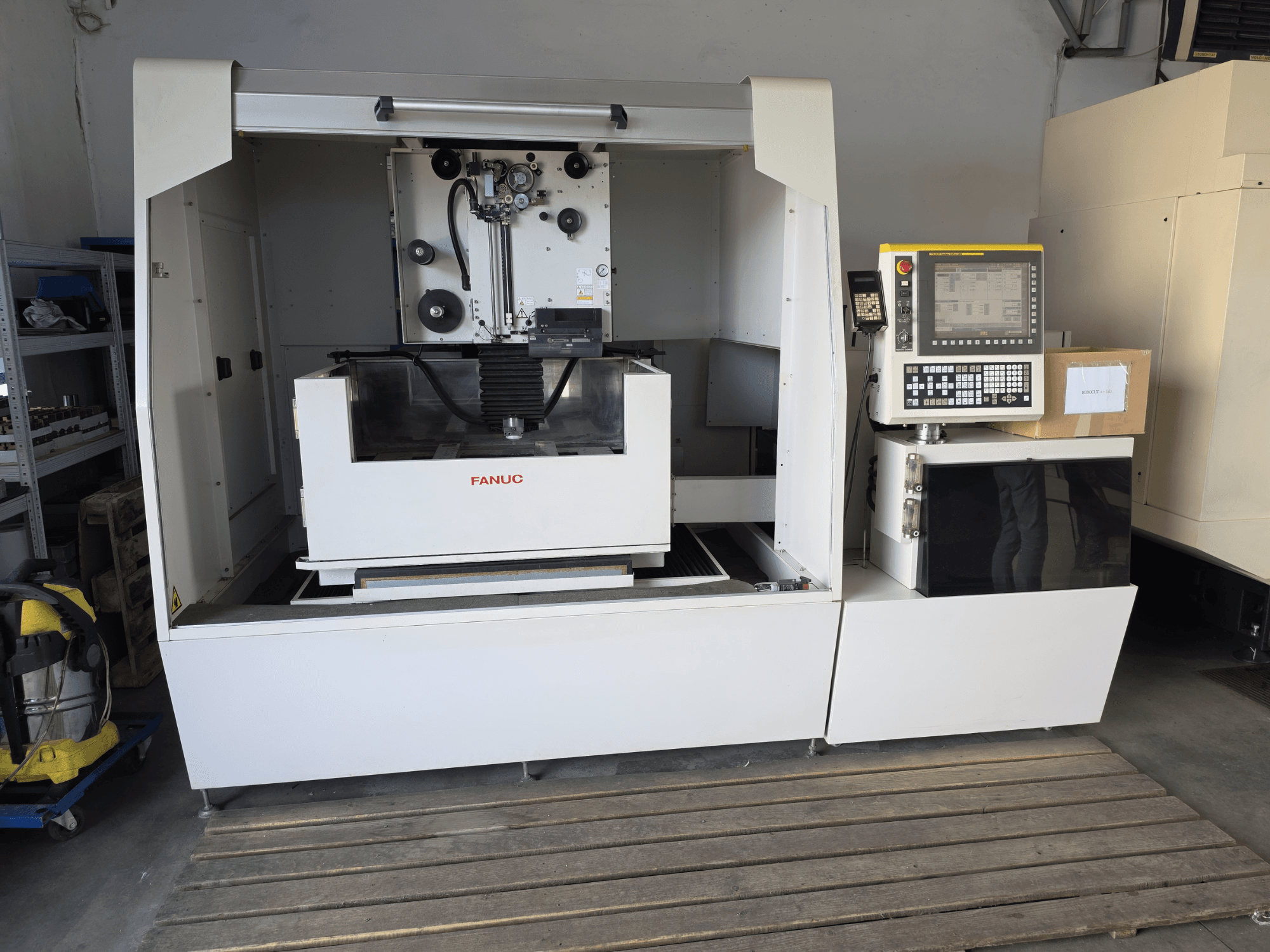 Máquina de electroerosión por hilo FANUC ROBOCUT alpha-1iD, vista frontal en la que se aprecian el panel de control, el área de trabajo y su diseño compacto en un entorno de taller.