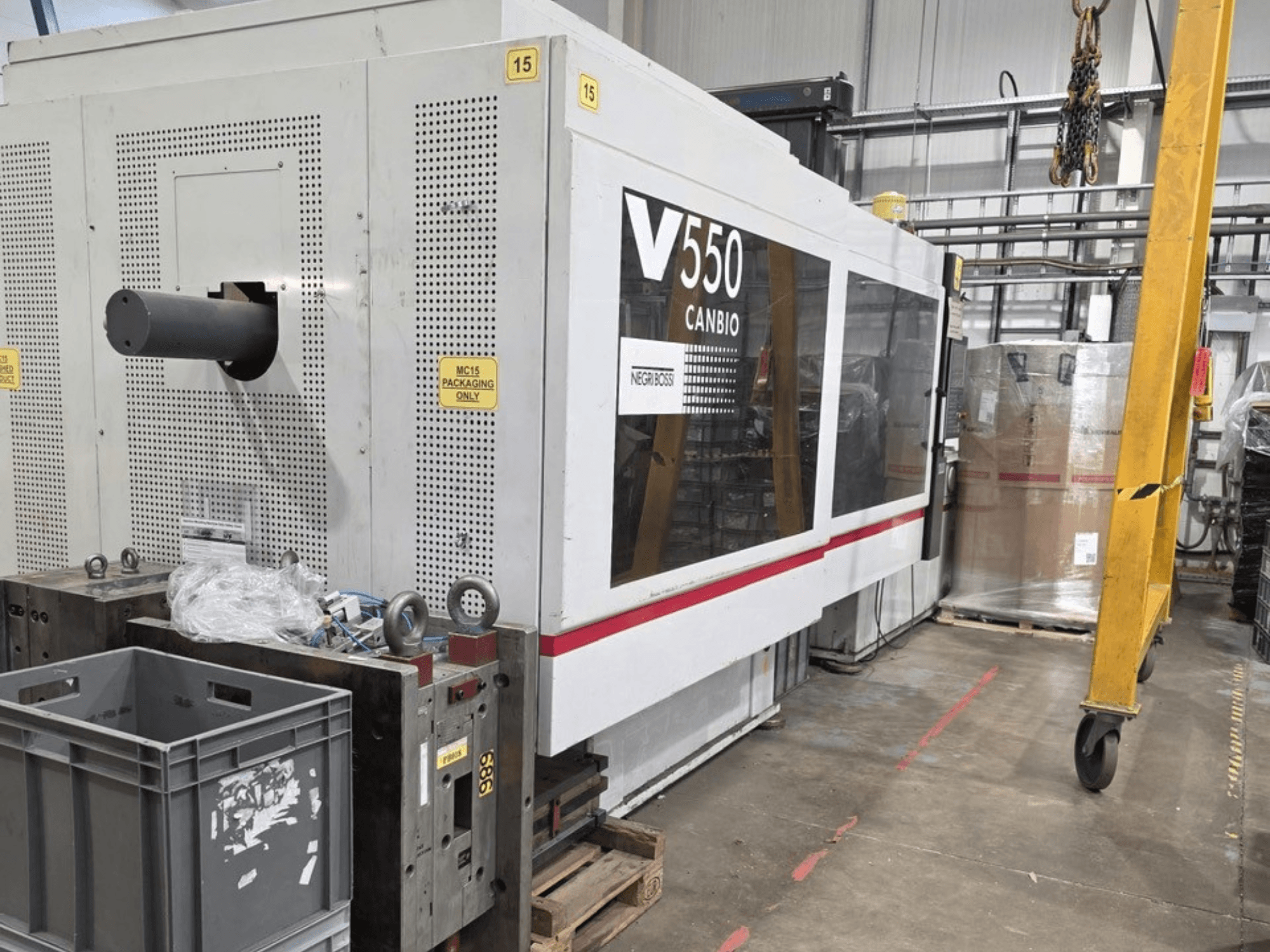 Máquina de moldeo por inyección hidráulica Negri Bossi V55000H-4250, vista lateral, con panel de control y cajas grises en primer plano.