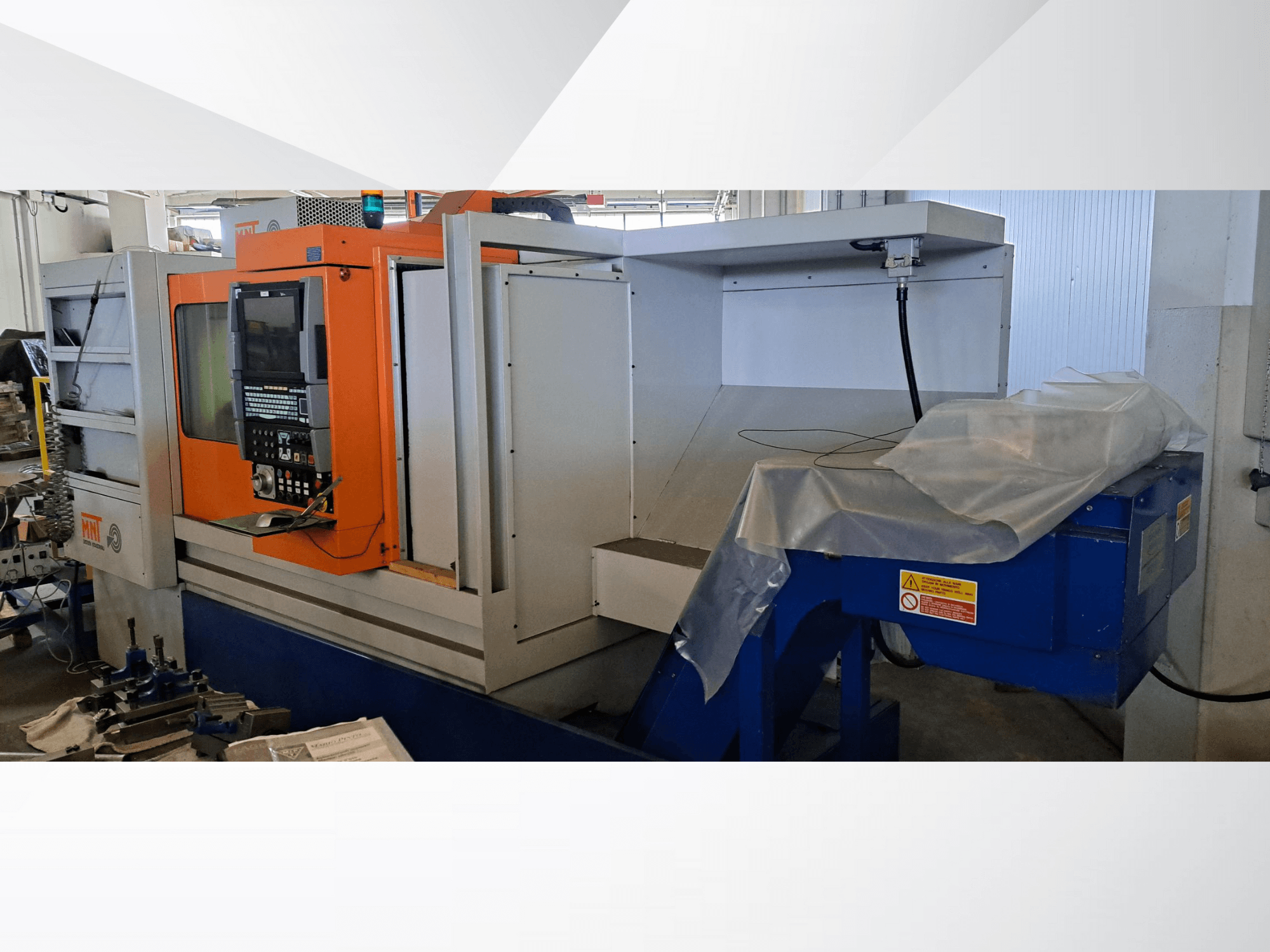 Máquina CNC MNT, vista frontal, con panel de control naranja, amplia zona de mecanizado y unidad azul de eliminación de virutas.