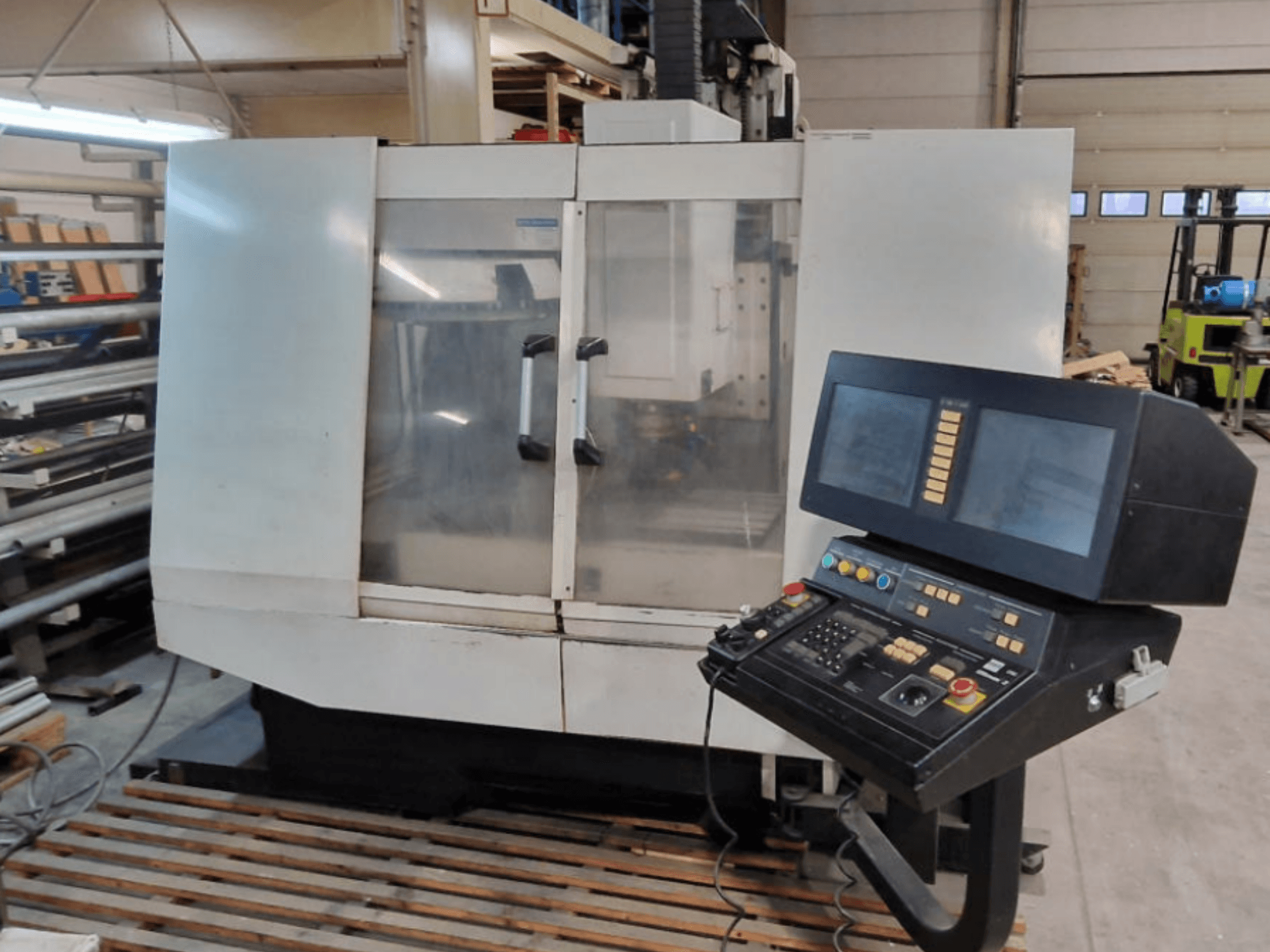 Centro de mecanizado vertical Hurco BMC30AP, vista frontal en la que se aprecia el panel de control con botones y pantallas, sobre un palé de madera.