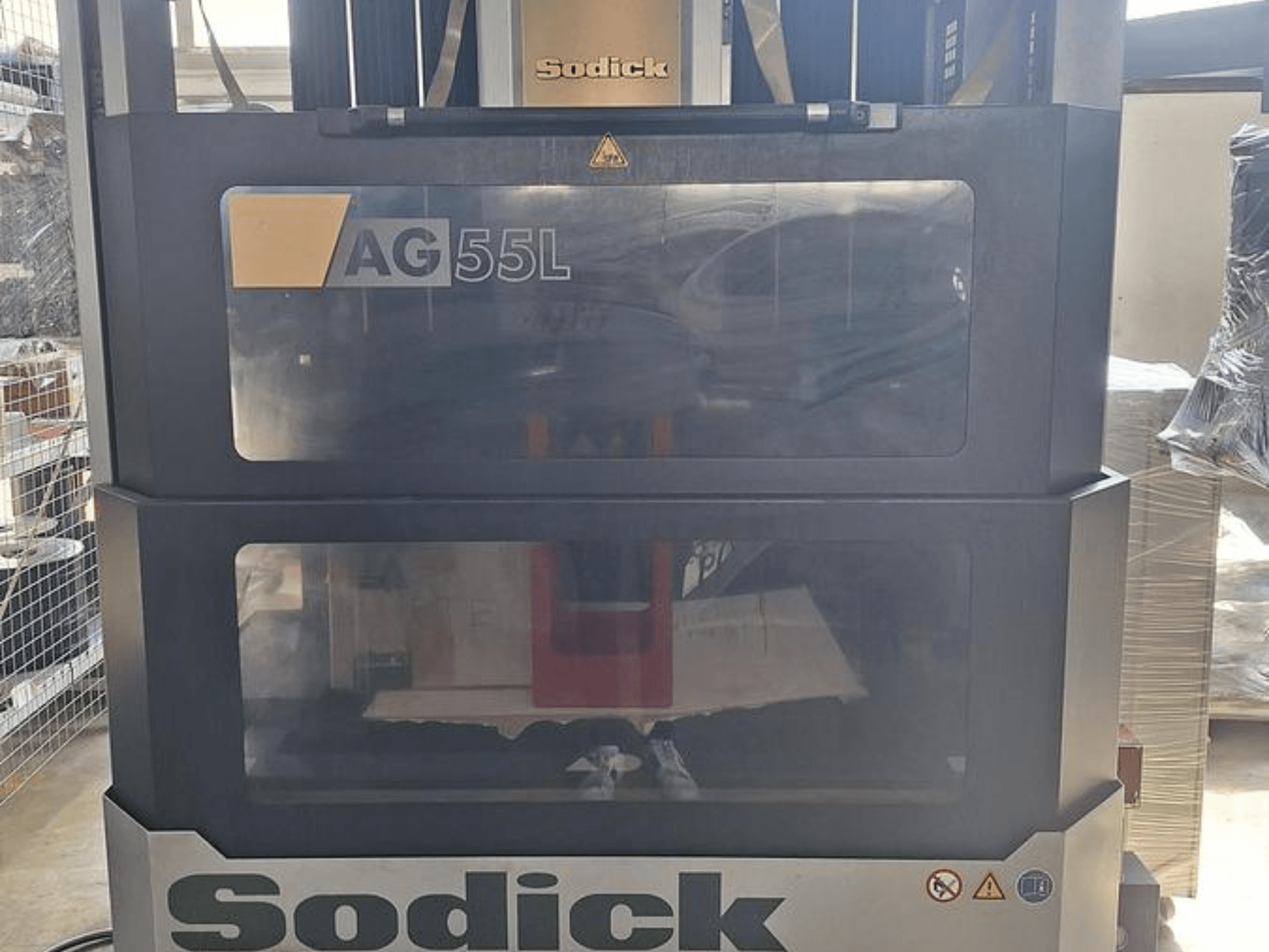 Máquina de electroerosión por penetración Sodick AG 55L, vista frontal con controles visibles a través de paneles transparentes, mostrando el espacio de trabajo en el interior.