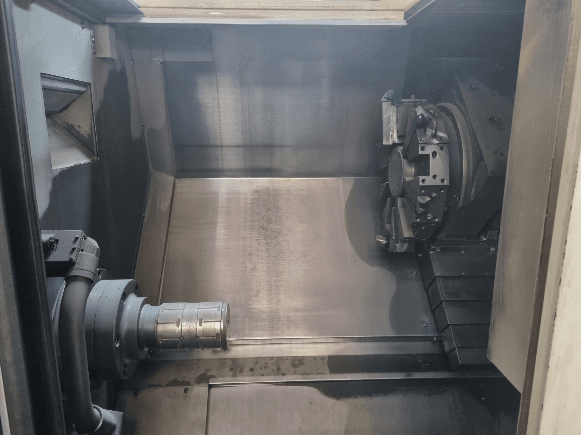 Vista interior de una máquina CNC que muestra un área de trabajo metálica, un portaherramientas y un mandril; destaca la ingeniería de precisión.