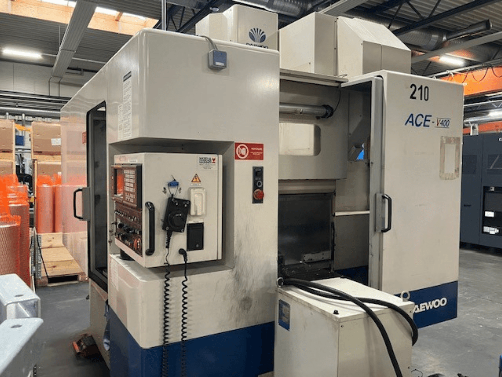 Máquina CNC Daewoo ACE-V400 en vista lateral, con panel de control, depósito de refrigerante y área de trabajo abierta.