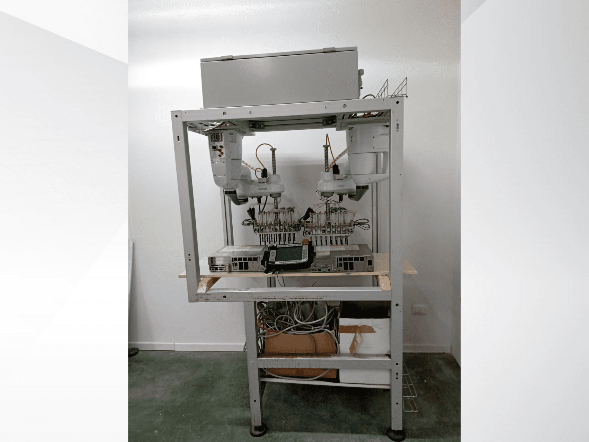 Estación de trabajo robótica automatizada con brazos dobles, unidad de visualización y electrónica en un bastidor metálico, vista frontal, configuración de tecnología avanzada.