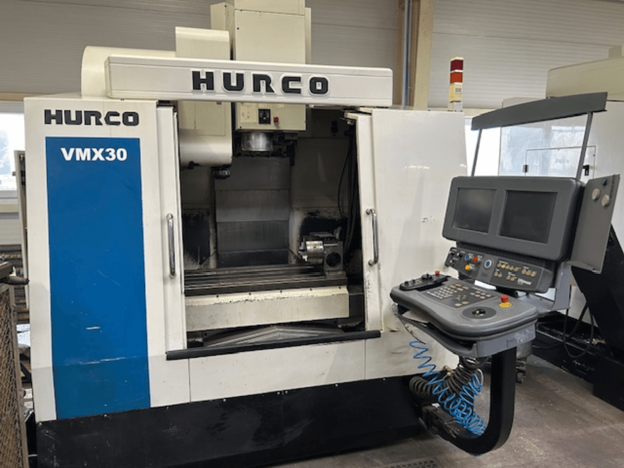 Fresadora CNC Hurco VMX30 en un taller, vista frontal; dispone de panel de control con pantallas dobles y botones operativos.