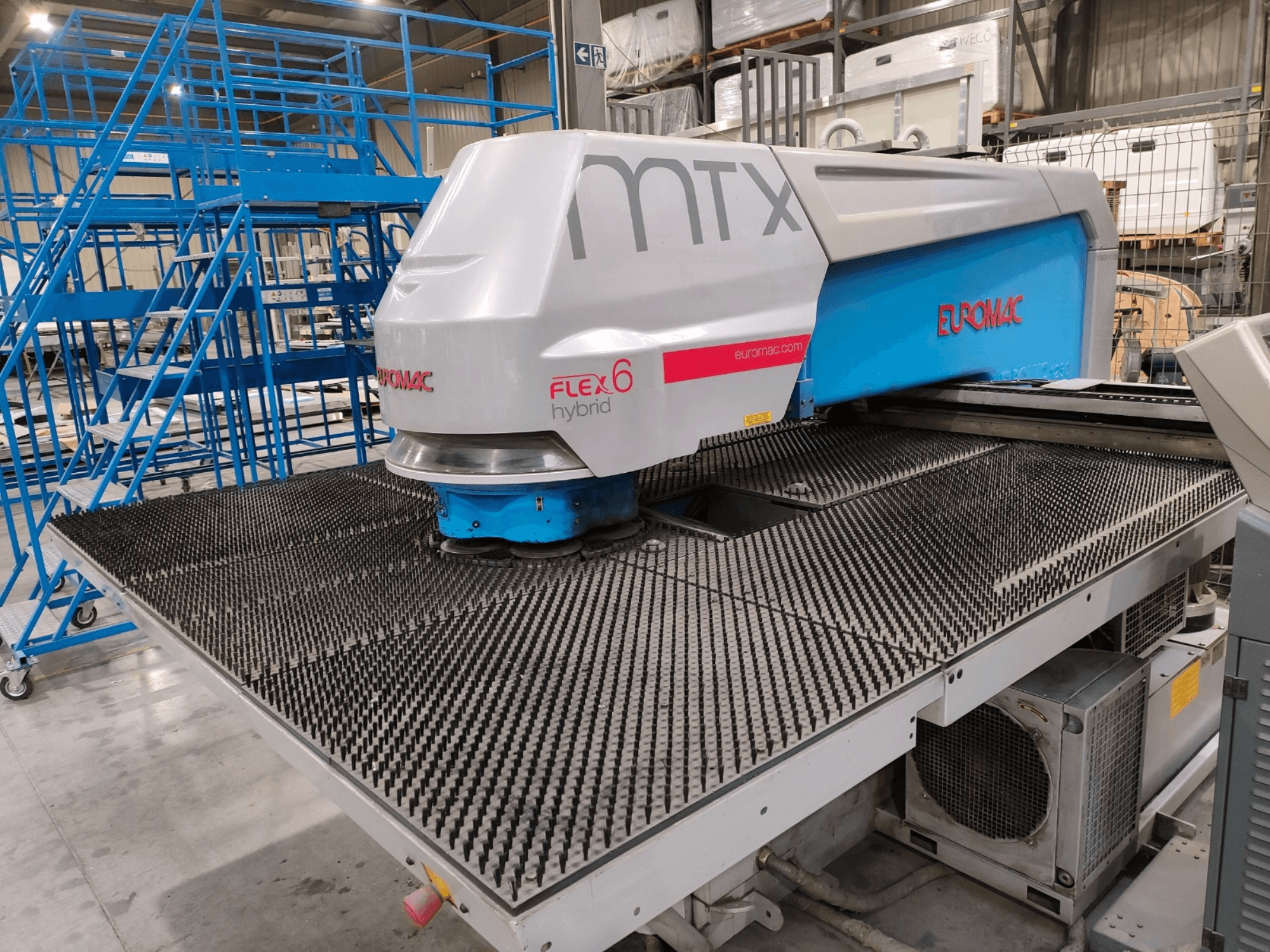Vista frontal de una máquina híbrida Euromac FLEX 6 con superficie de corte texturizada, colocada en un entorno de almacén.