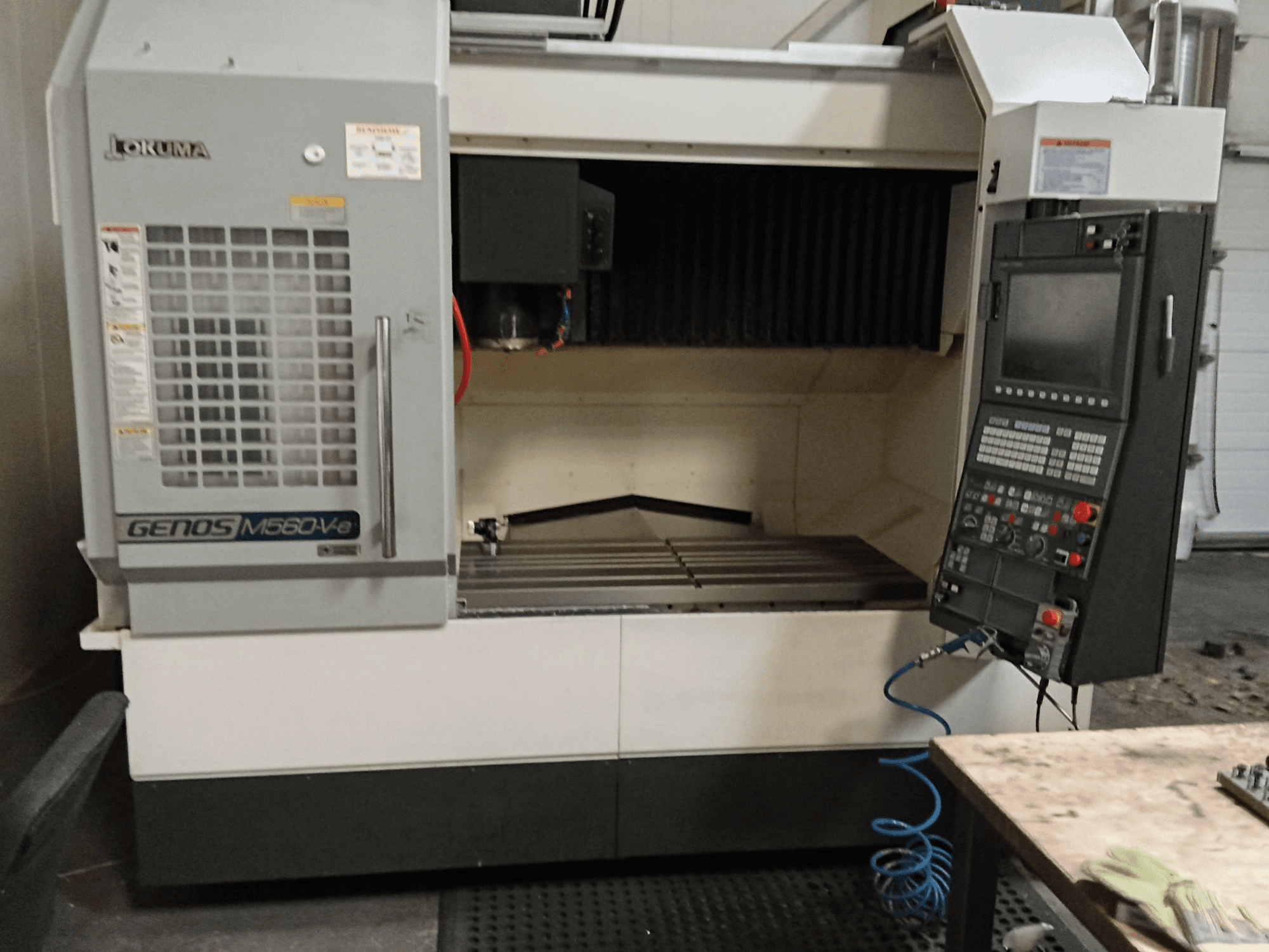 Okuma GENOS M560-V, vista frontal de un centro de mecanizado vertical con panel de control, interfaz CNC y área de corte visible.