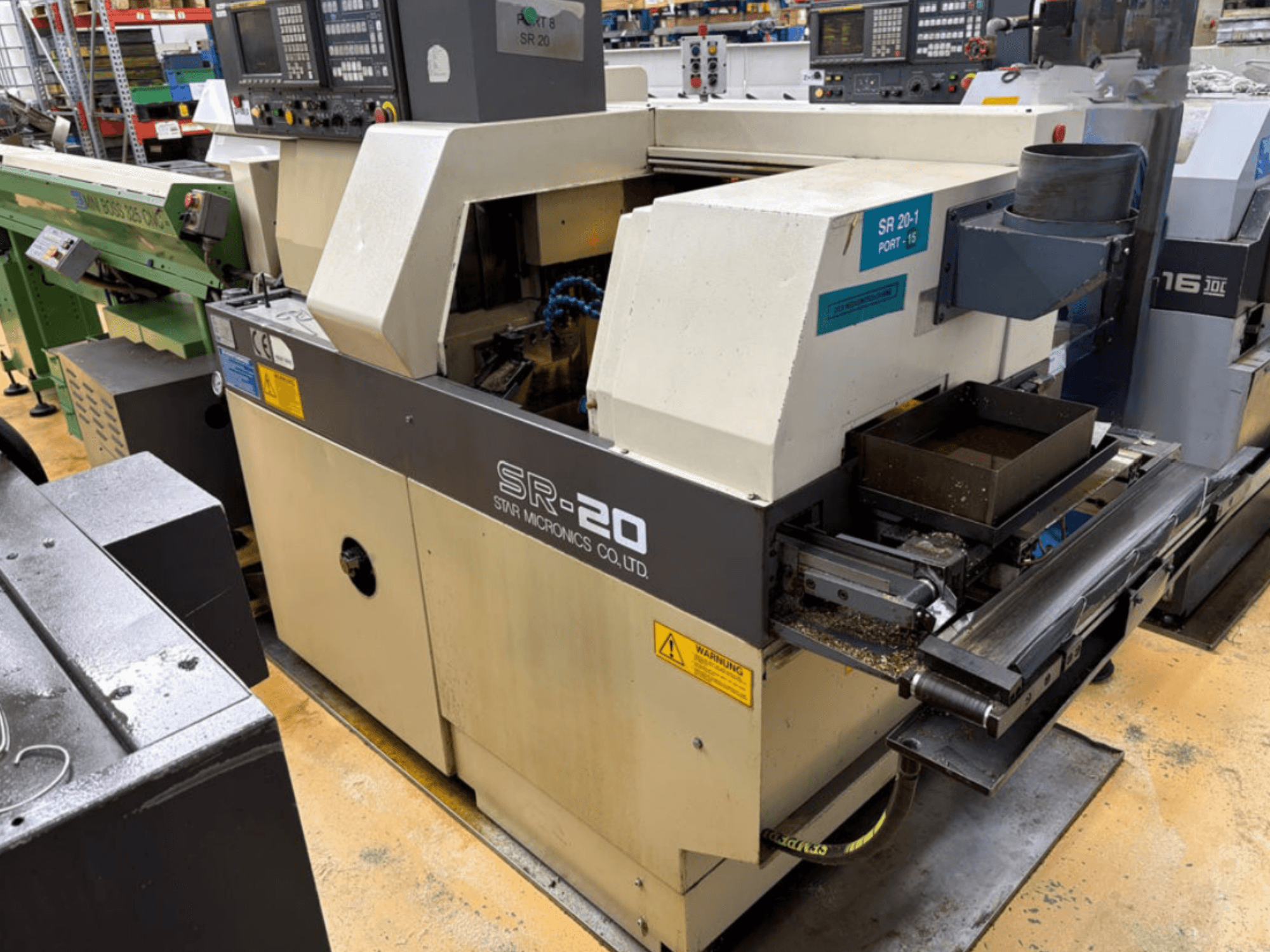 Torno de tipo suizo STAR MICRONICS SR20 en vista lateral, en el que se aprecian el panel de control y la zona de herramientas con virutas.