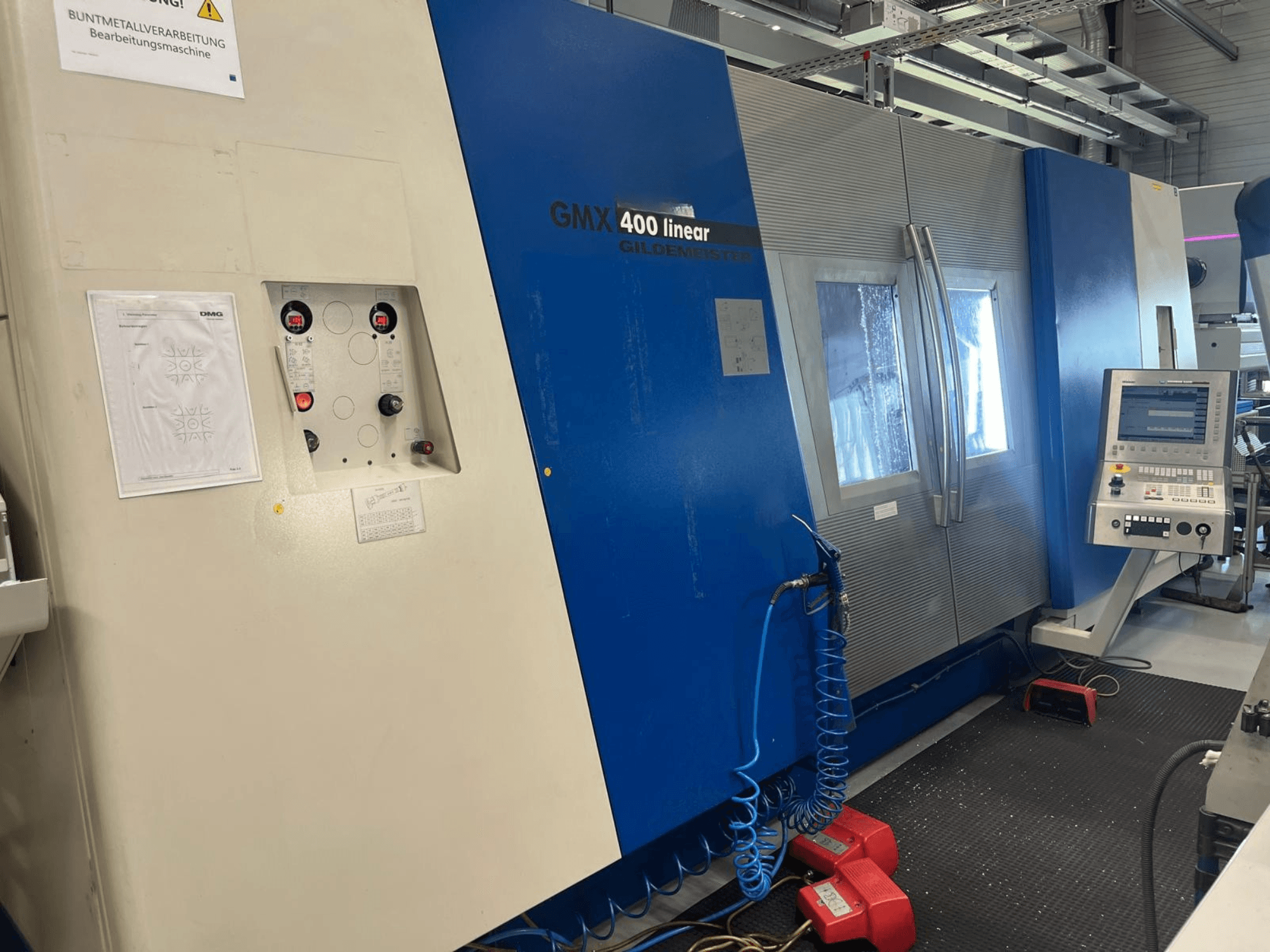 Centro de torneado y fresado lineal Gildemeister GMX 400, vista frontal en la que se aprecian el panel de control, el sistema de refrigeración y los botones de funcionamiento.