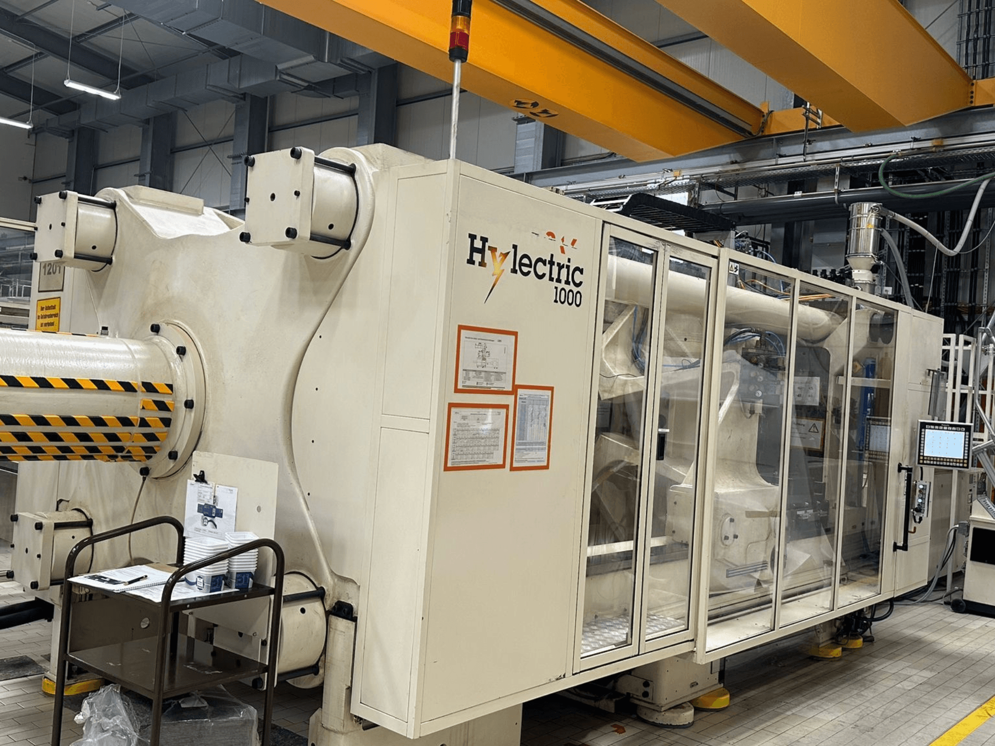 Máquina de moldeo por inyección eléctrica Husky Hylelectric H1000 RS95/80, vista lateral en la que se aprecian el panel de control y los dispositivos de seguridad.