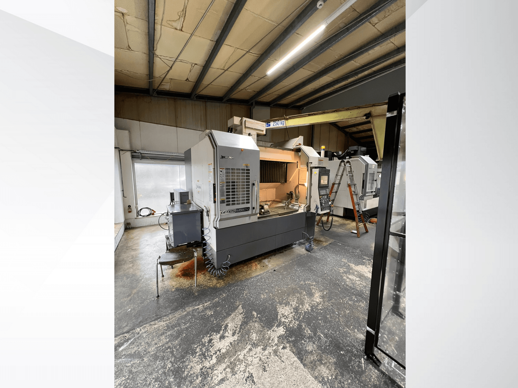 Máquina CNC GRETOS 750 en un taller, vista frontal, mostrando el panel de control y la zona de trabajo con herramientas, escalera visible al fondo.