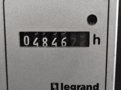 Contador horario Legrand que muestra 048467.6, vista frontal con luz indicadora roja y dígitos negros sobre fondo claro texturizado.