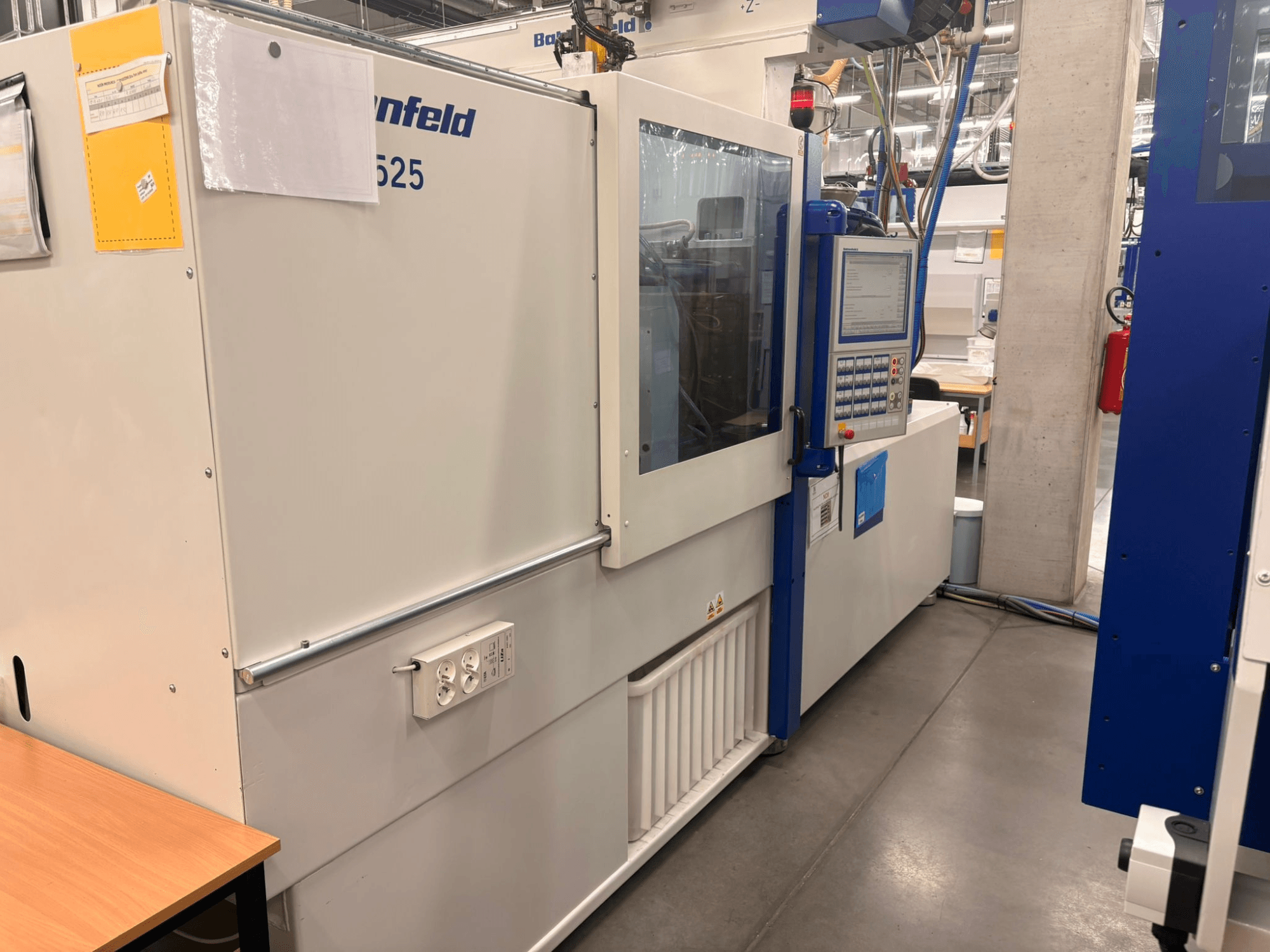 Máquinas de Arburg, modelo 620S, vista frontal que muestra el panel de control y los puertos de alimentación en un entorno de fábrica.