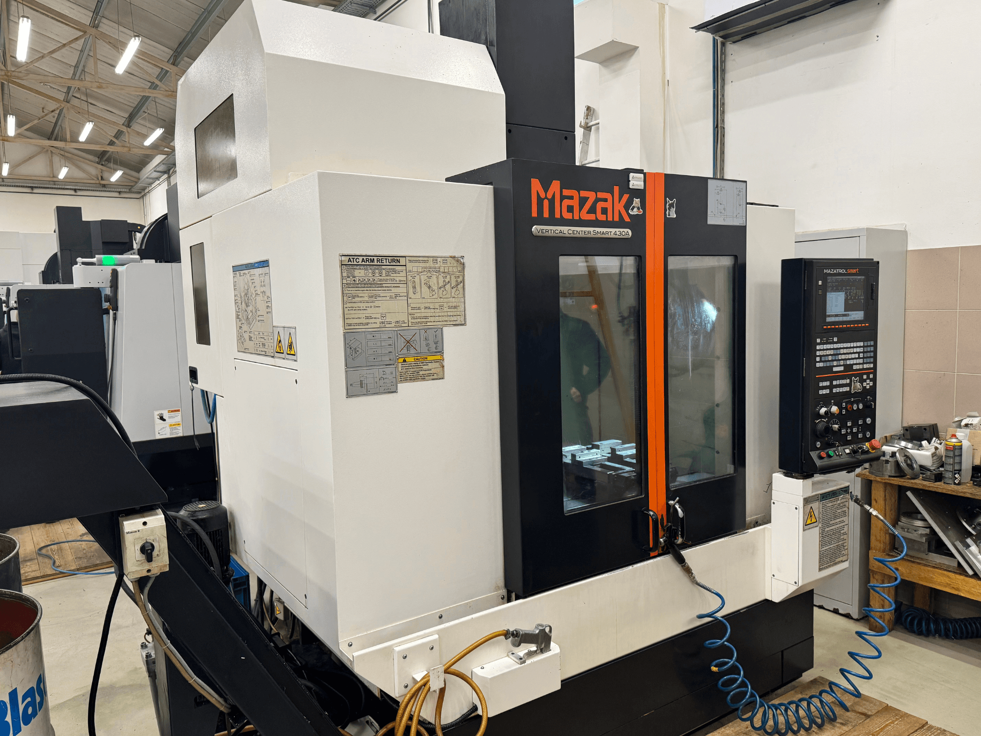 Mazak Vertical Center Smart 430A, vista frontal; fresadora CNC con panel de control, carcasa transparente y portaherramientas visibles.