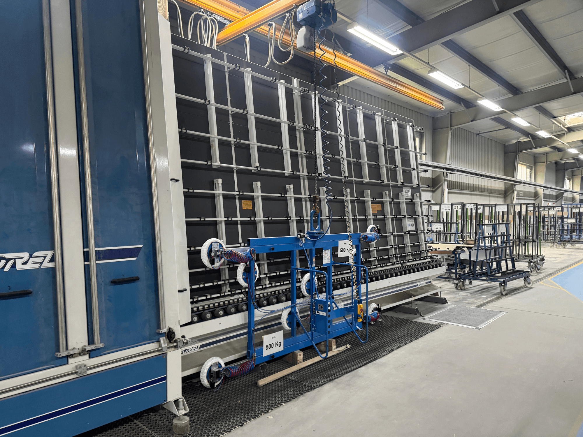 Equipo industrial de Drel, con un gran bastidor y mecanismo de elevación, mostrado desde una vista lateral en una fábrica.