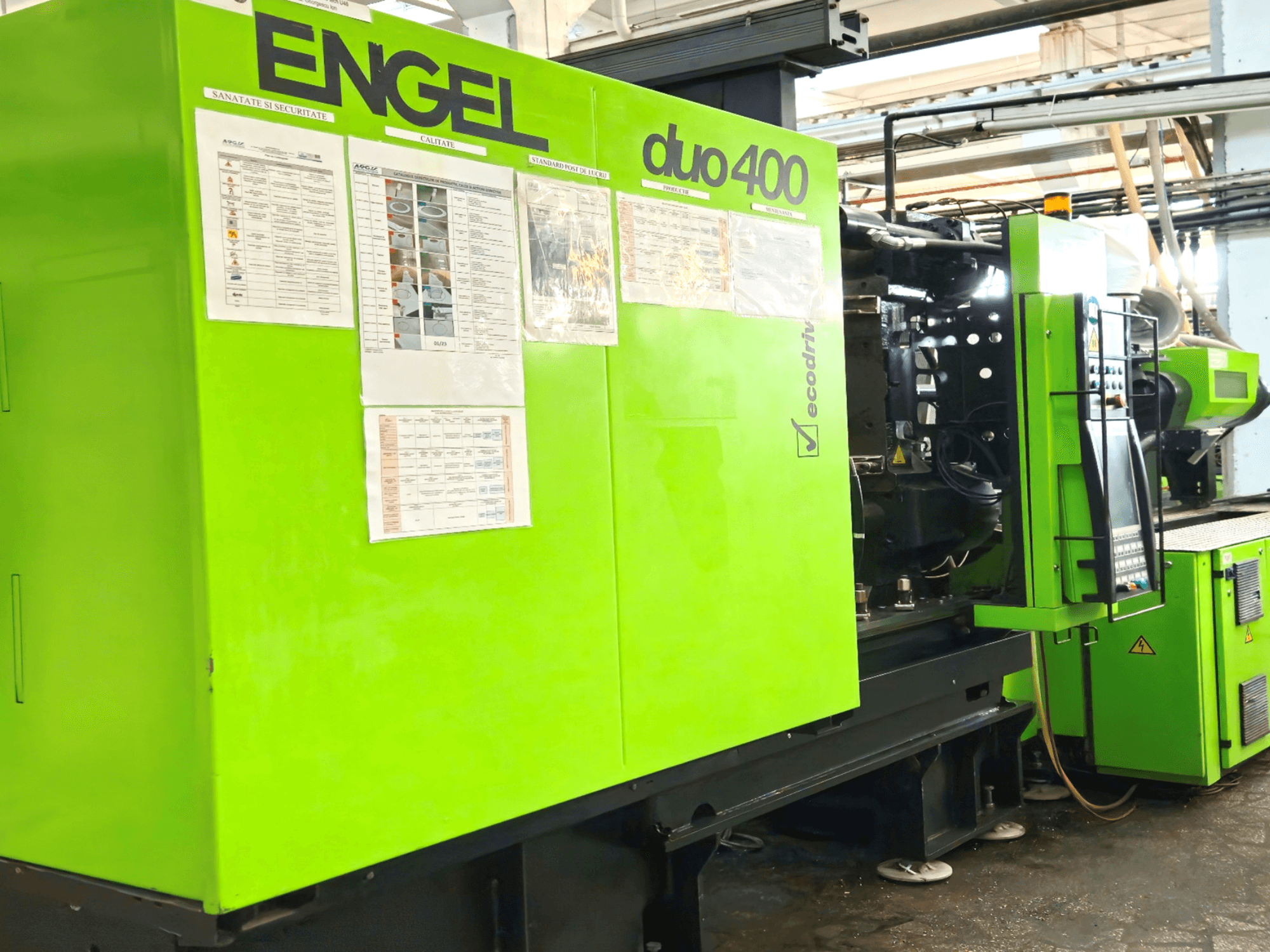 Máquina de moldeo por inyección ENGEL duo 400 verde, vista frontal, mostrando el panel de control y la documentación de seguridad en el exterior.