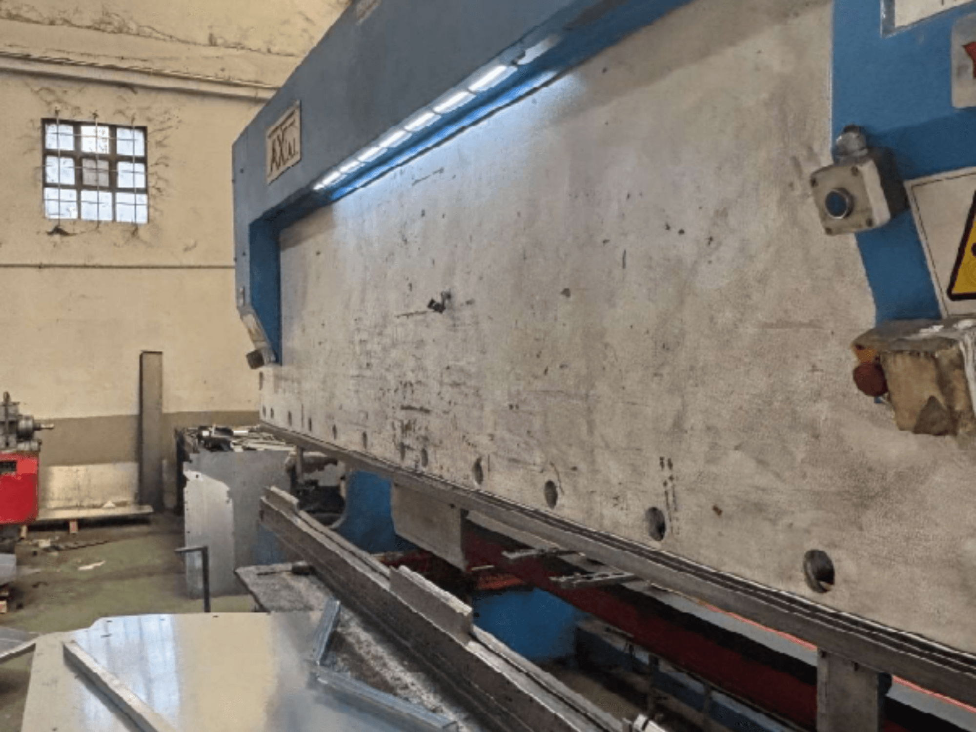 Sistema de manipulación de palés Axial PHS-W-124 en un taller, vista lateral que muestra la superficie de trabajo y los detalles del panel de control.