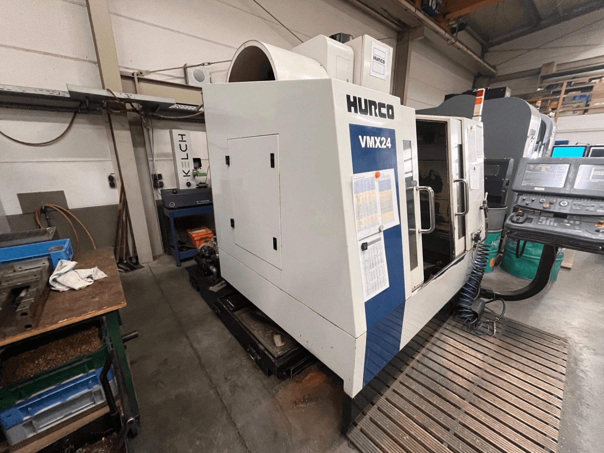 Máquina CNC Hurco VMX24 en un taller, vista frontal; cuenta con un panel de control y una puerta de acceso abierta.
