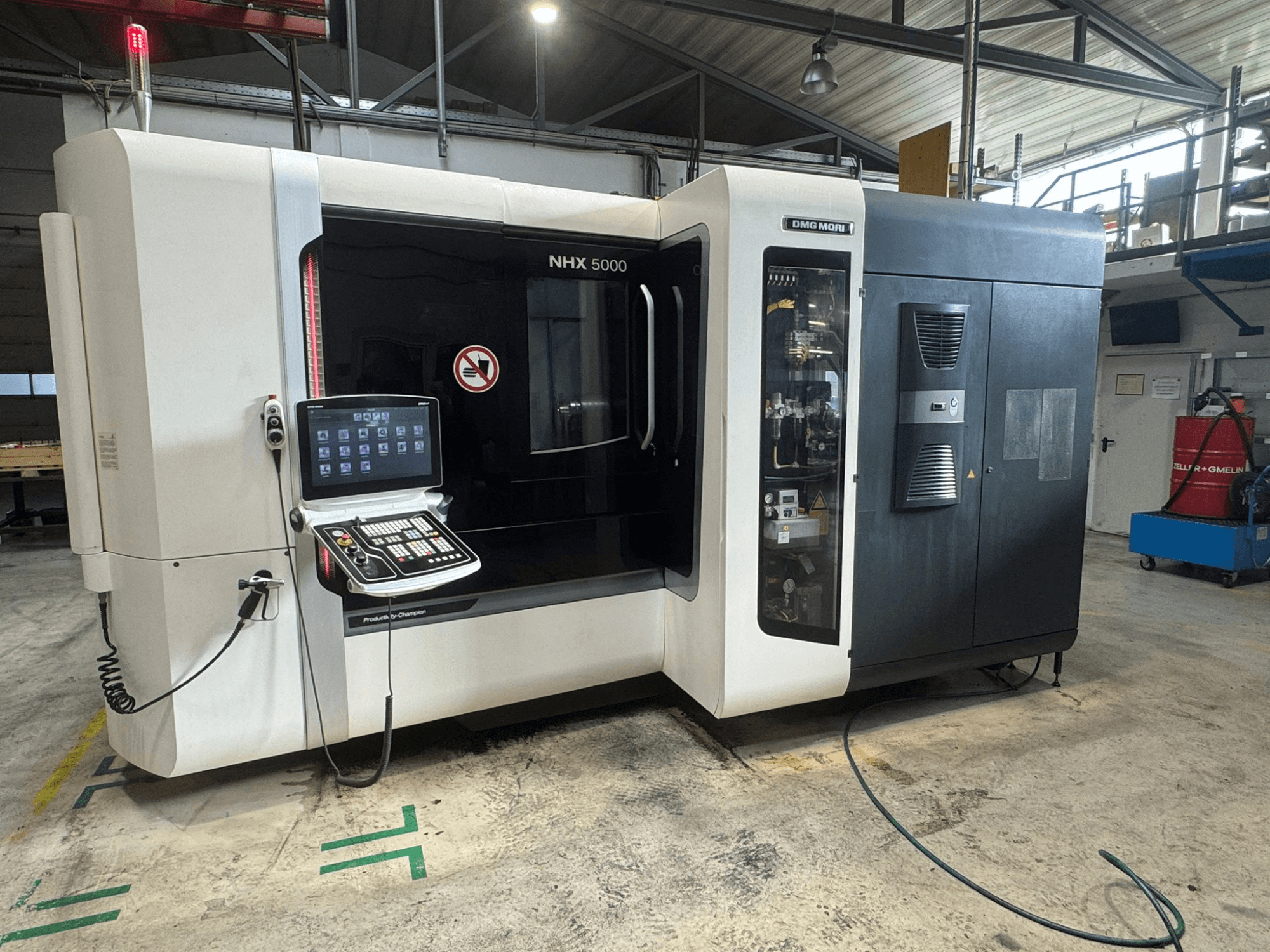 Centro de mecanizado horizontal DMG MORI NHX 5000, vista frontal con panel de control visible e indicadores de seguridad.