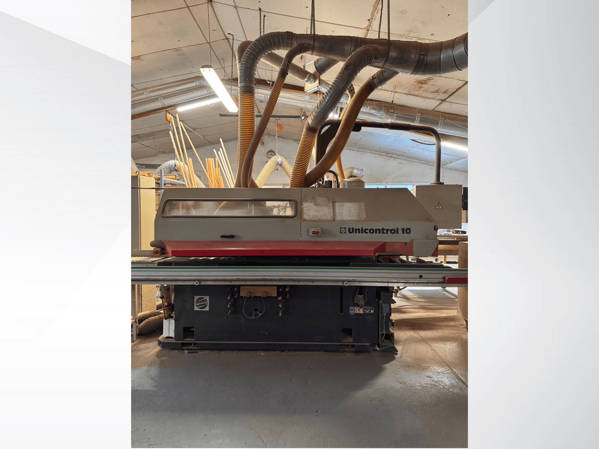 Vista frontal de una máquina Unicontrol 10 para trabajar la madera, con tubos de extracción de polvo y controles operativos.