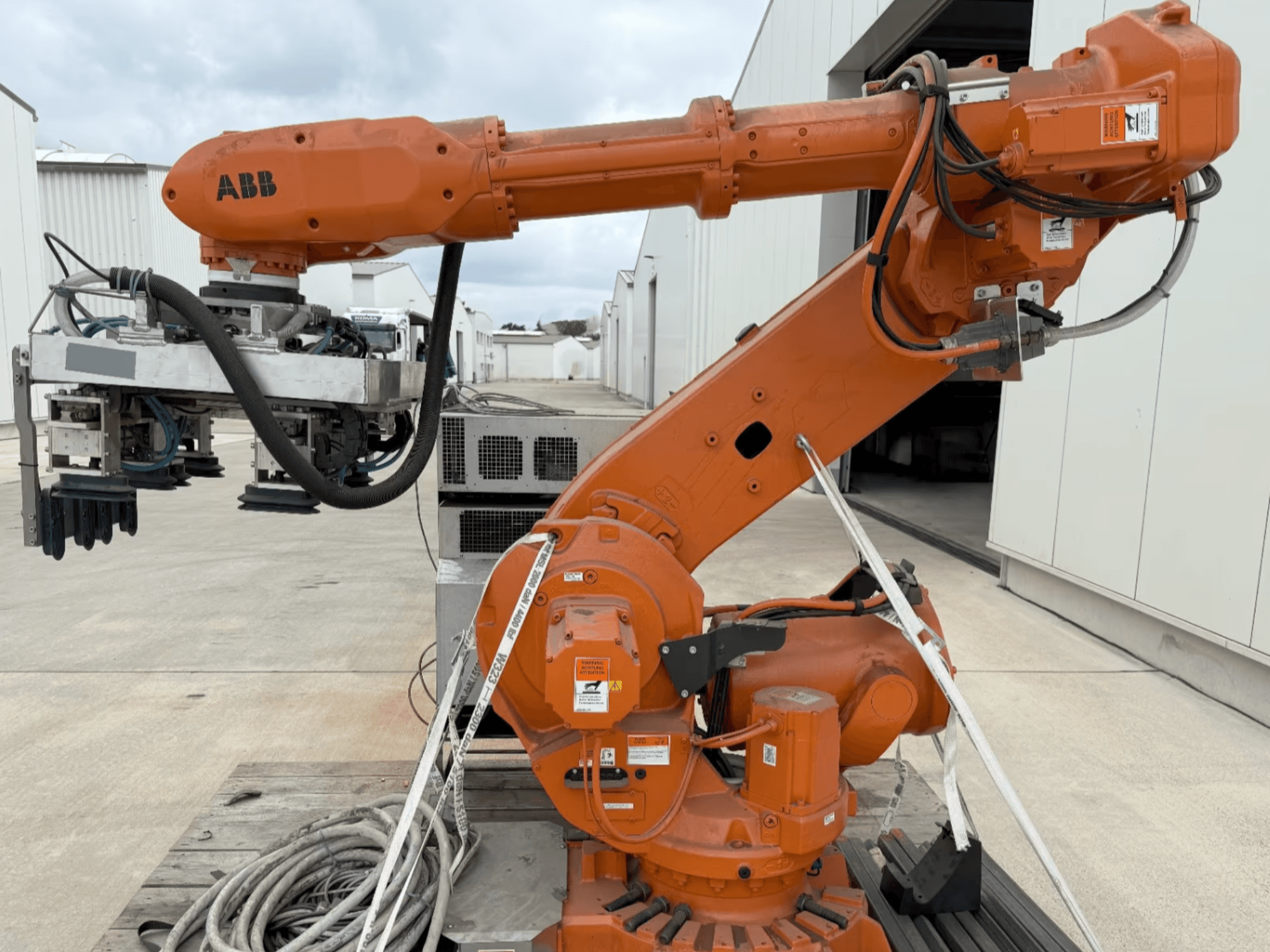 Brazo robótico ABB RB 6600-130/3.2 en vista lateral, con un brazo robótico naranja con un accesorio de agarre y cableado visible.
