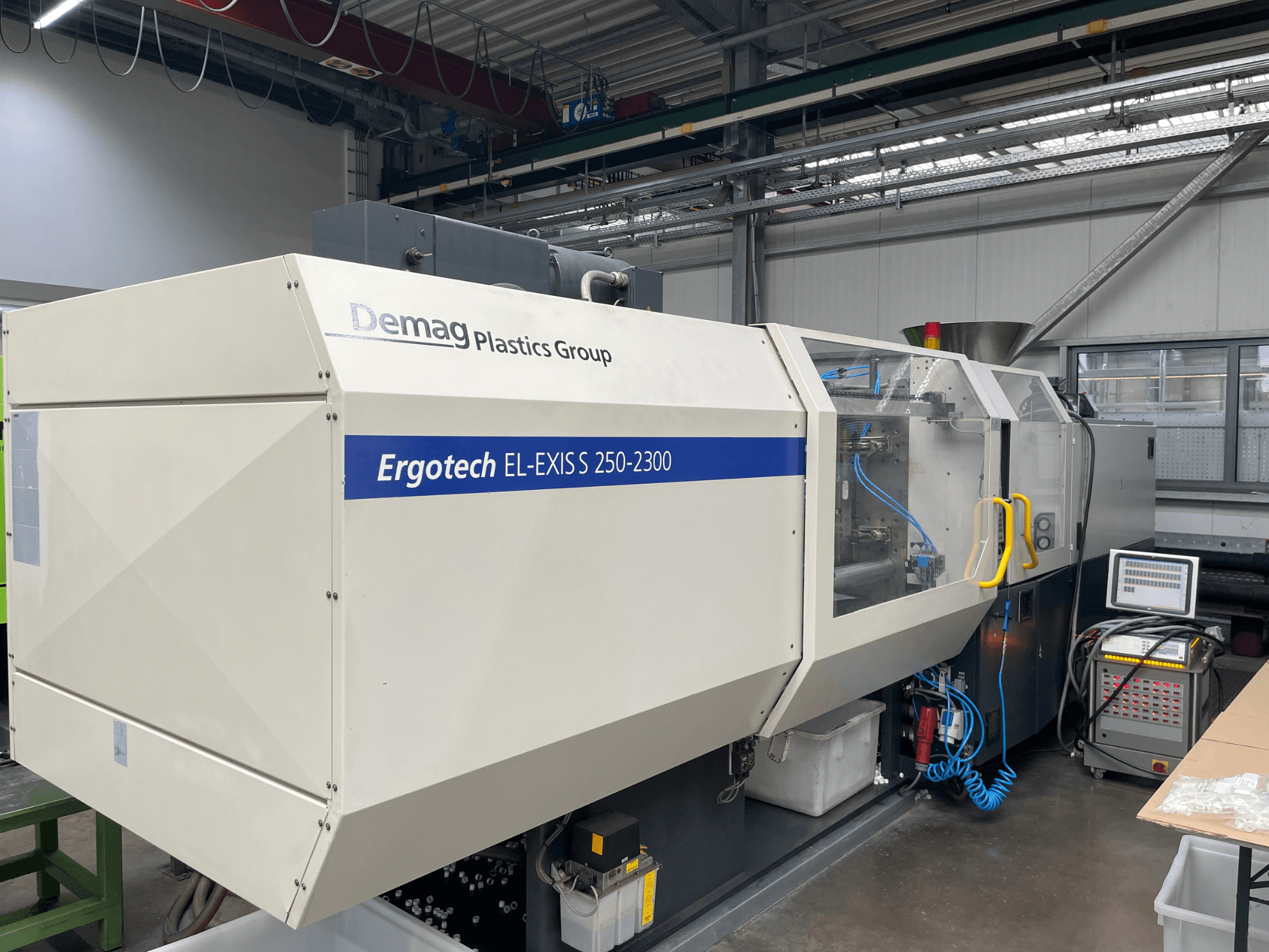 Máquina de moldeo por inyección Demag Ergotech EL-EXIS S 250-2300, vista lateral, mostrando el panel de control y el sistema de alimentación.