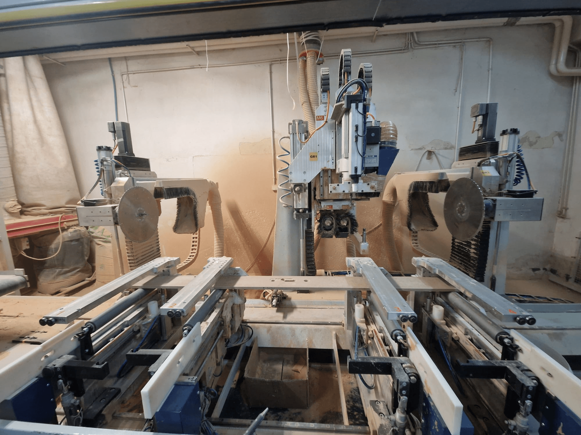 Máquina CNC con dos hojas de sierra y raíles, vista de frente. Sistemas de extracción de polvo visibles, adecuados para trabajar la madera.