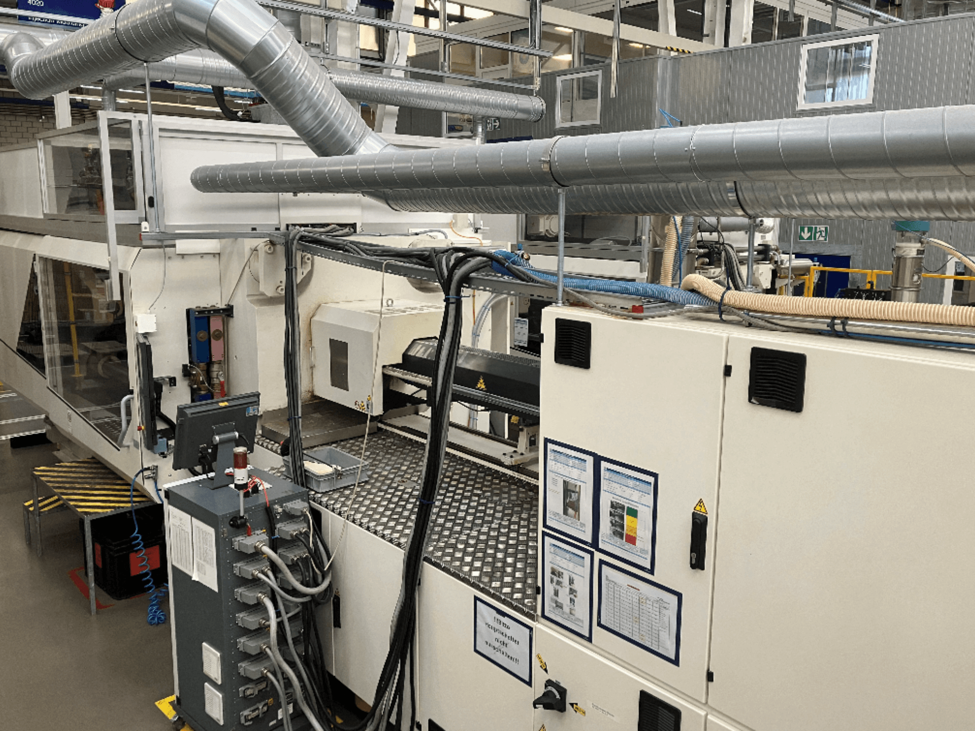 Maquinaria industrial con numerosas tuberías, paneles de control y manuales de funcionamiento, vista desde arriba.