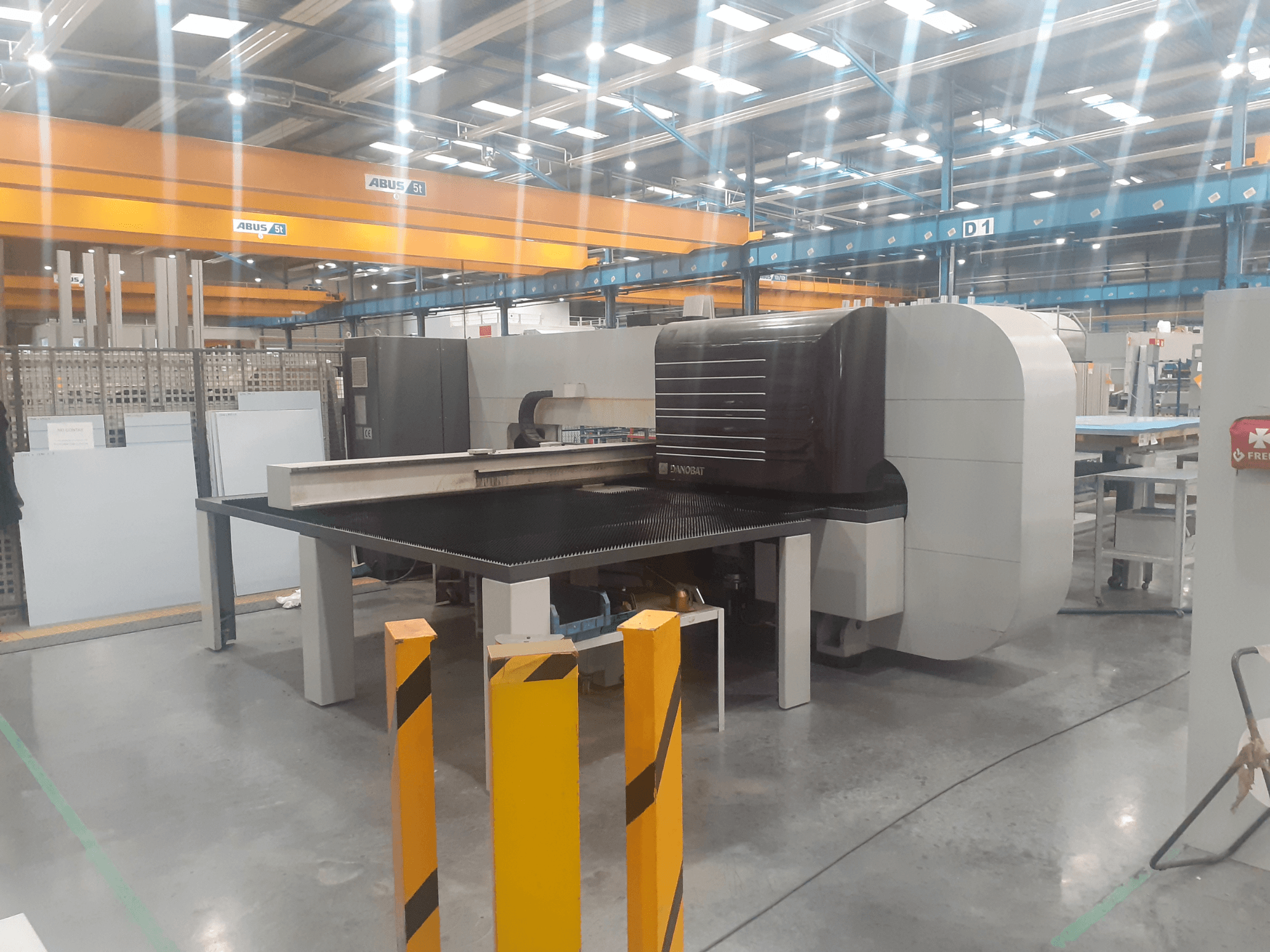 Rectificadora cilíndrica DANOBAT CHROMA 30 en taller, vista lateral mostrando gran mesa y barreras de seguridad en primer plano.