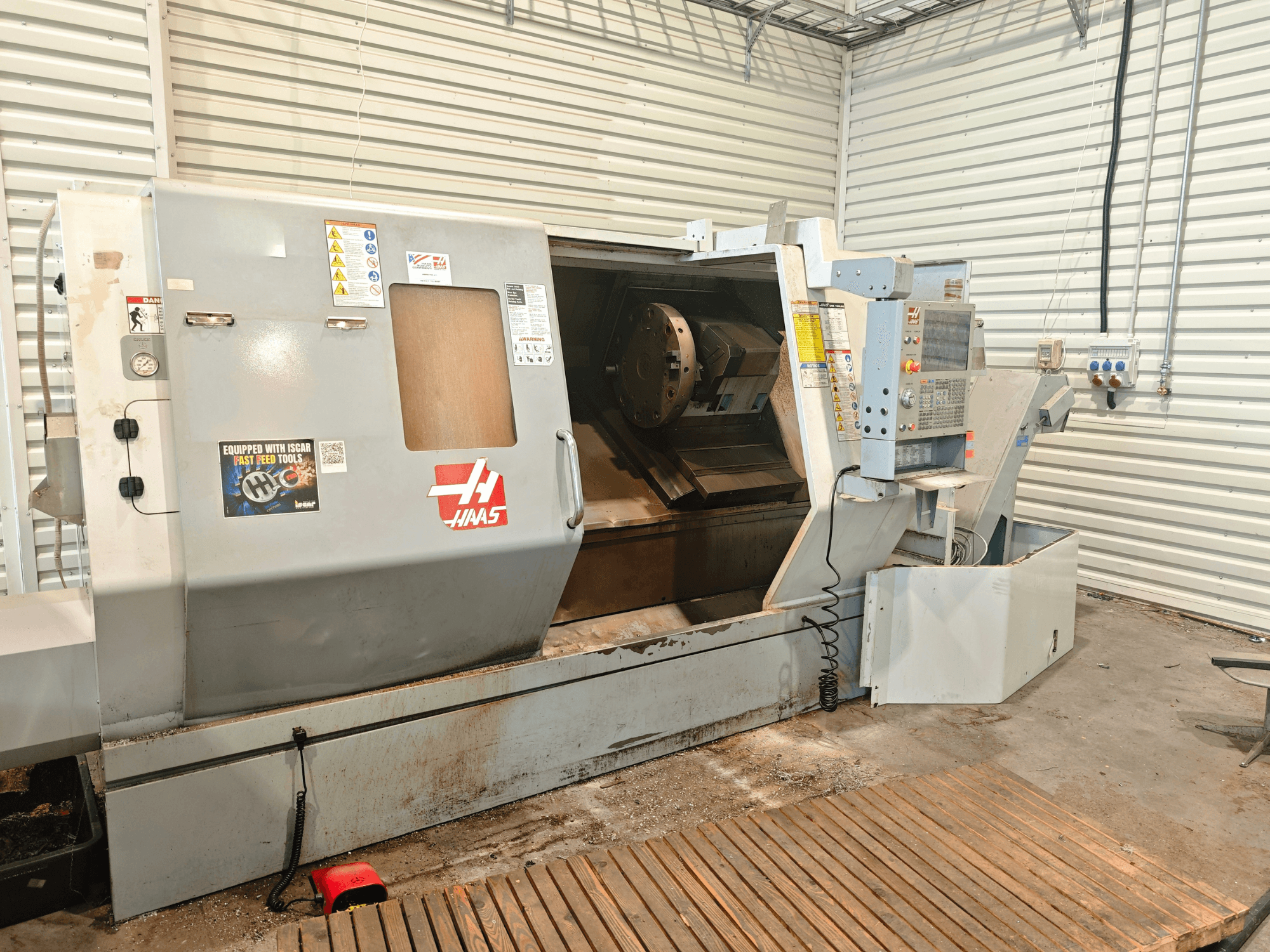 Torno horizontal Haas SL-40HE, vista frontal, en la que se aprecian el panel de control, la zona de trabajo y las etiquetas de seguridad.