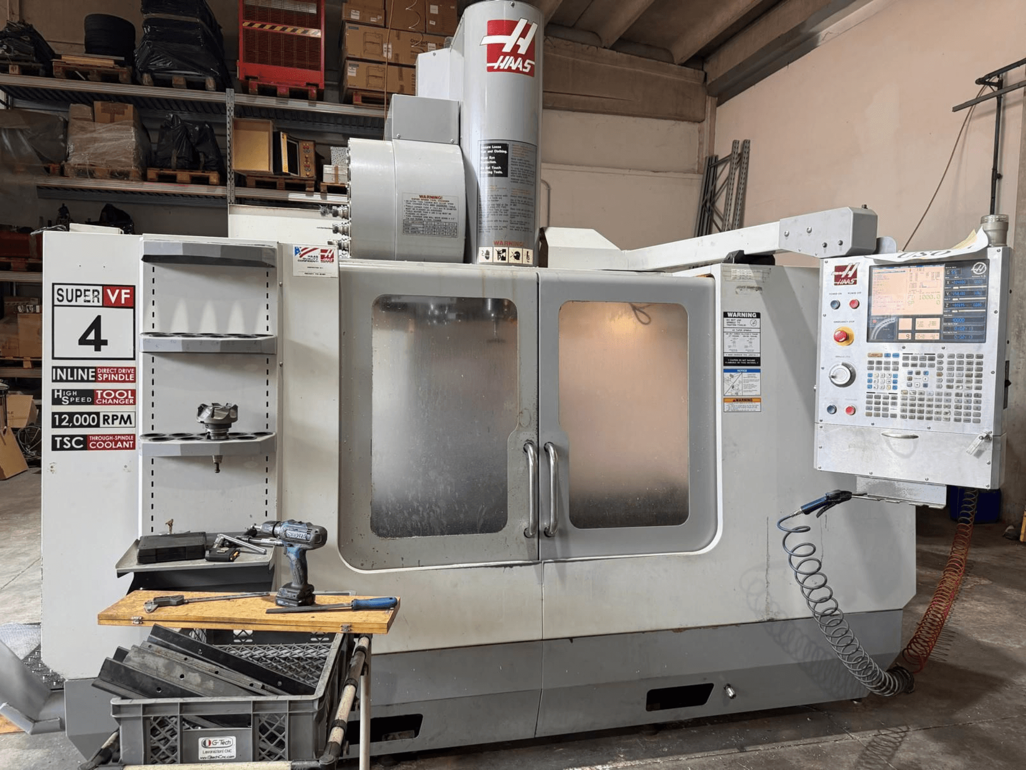 Vista frontal del centro de mecanizado vertical HAAS VF-4SSHE con paneles de control, portaherramientas y husillo de 12 000 rpm; máquina de alta velocidad y precisión.