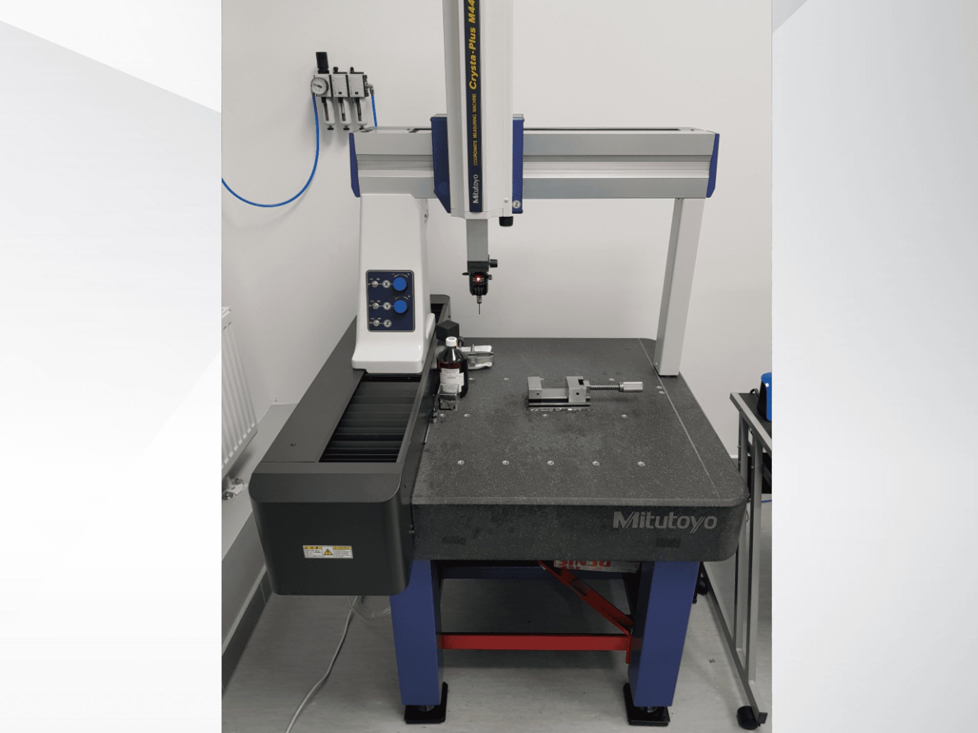 Máquina de medición por coordenadas (CMM) Mitutoyo Crysta-Plus M443 vista desde delante, en la que se aprecian la sonda de medición, el panel de control y la mesa de inspección con los accesorios.