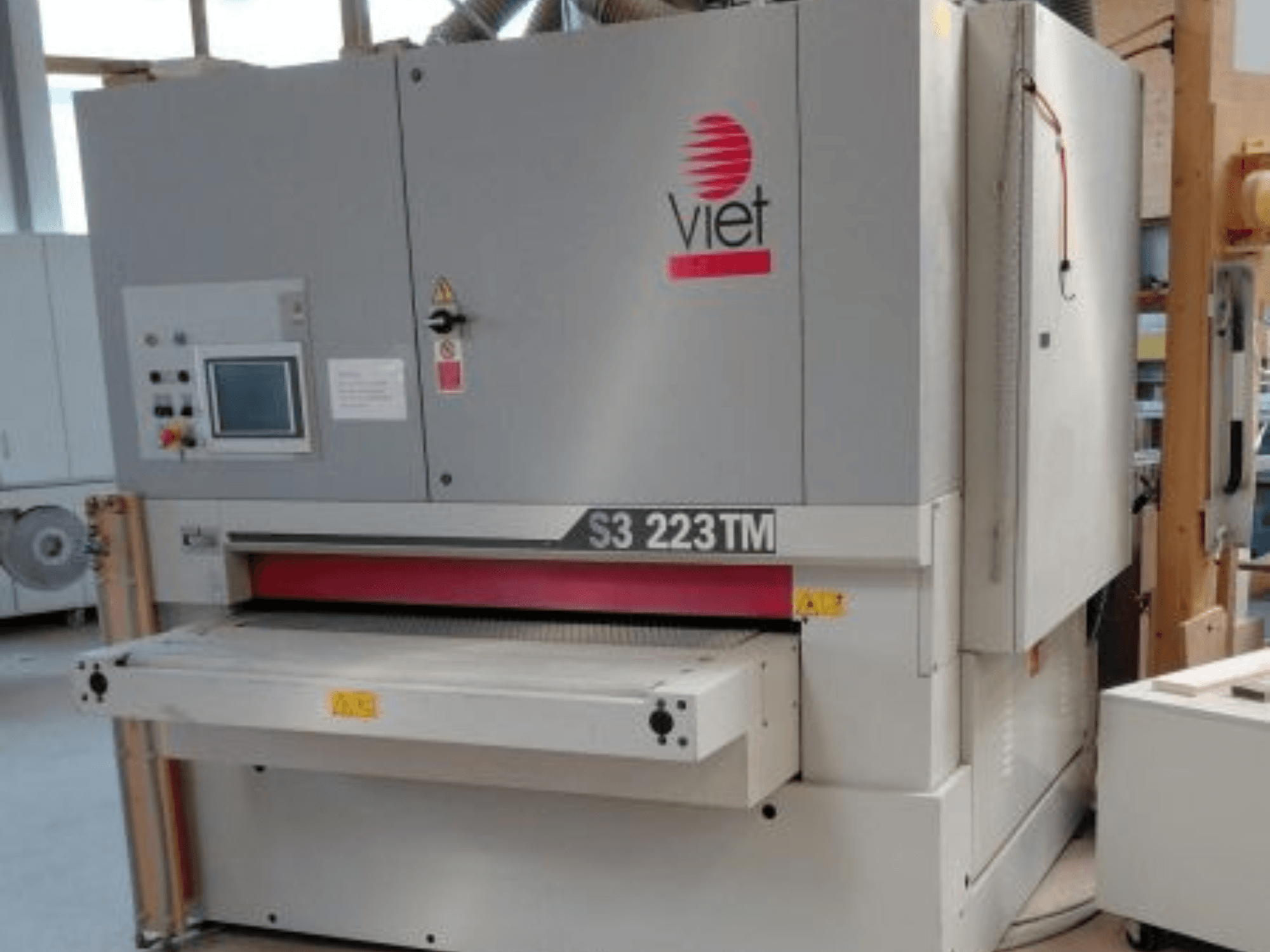 Lijadora de banda VIET S3 223TM vista desde delante, en la que se aprecian el panel de control, la mesa de lijado y las etiquetas de seguridad.