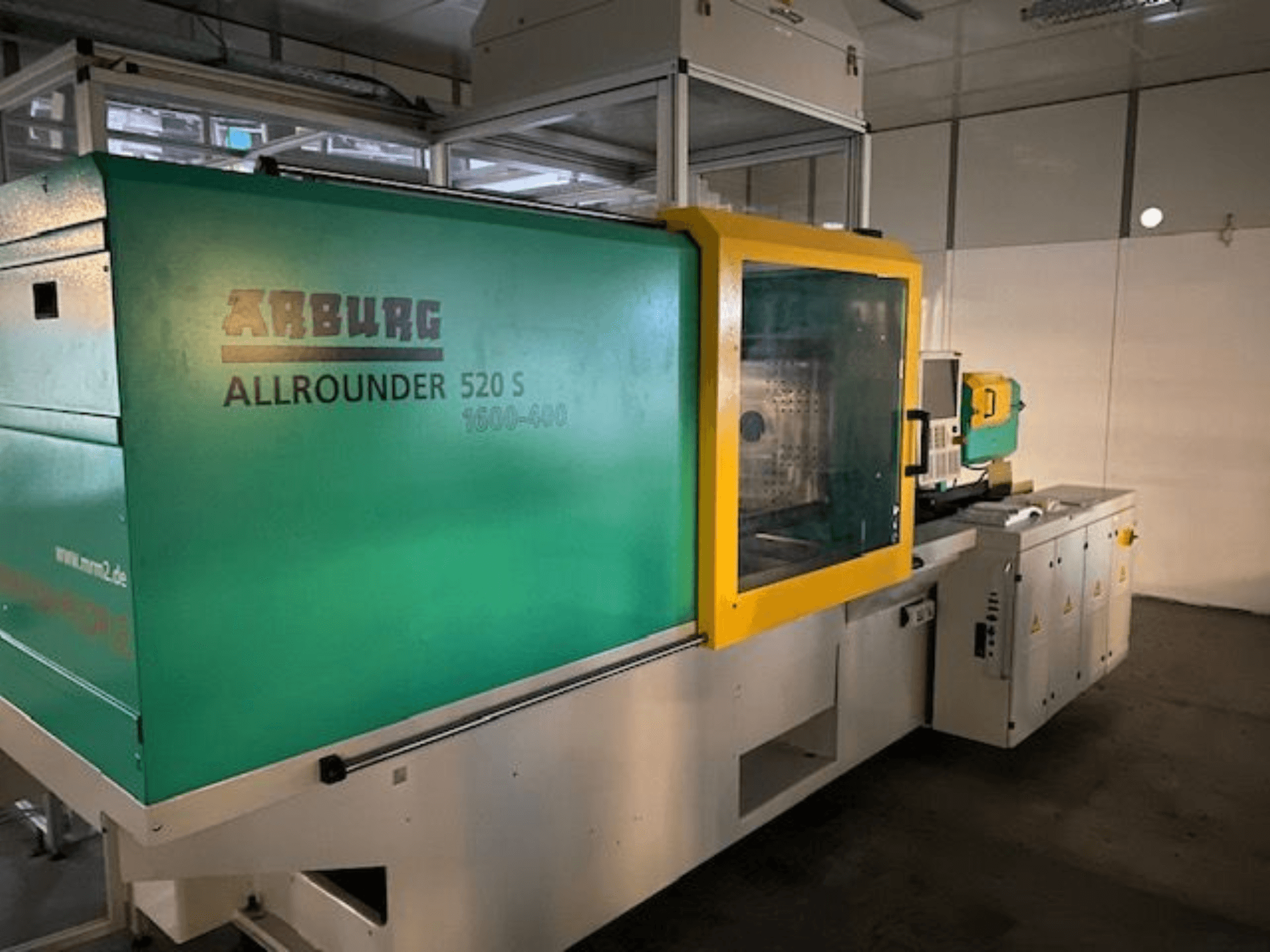 Máquina de moldeo por inyección Arburg Allrounder 520 S, vista lateral, con exterior verde y amarillo, detalles técnicos visibles.