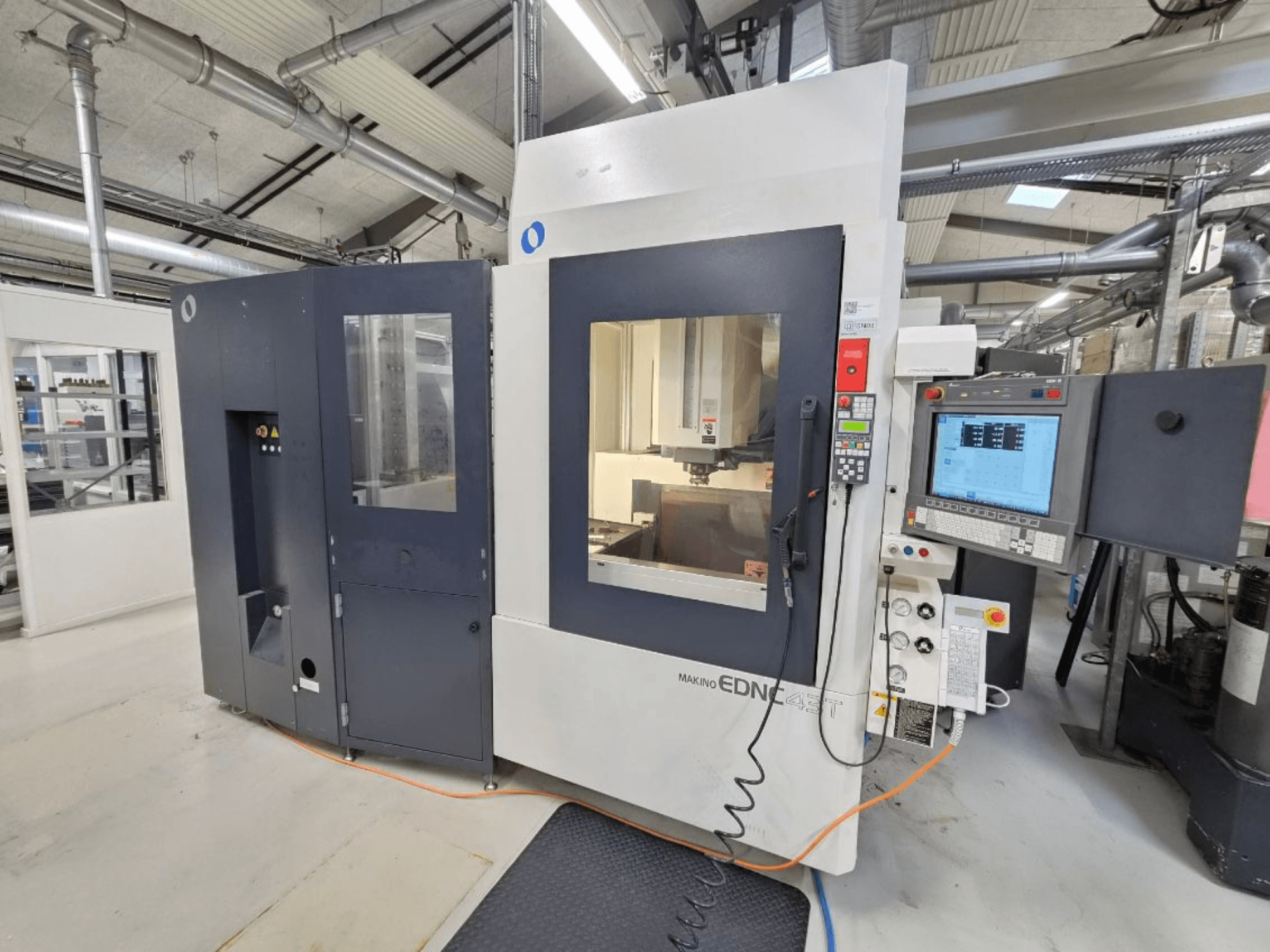 Vista frontal de una máquina de electroerosión por penetración Makino EDNC 43T, en la que se aprecian el robot Erowa, los mandos y el espacio de trabajo.