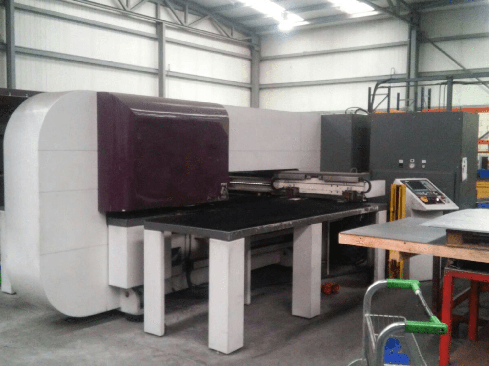Máquina industrial morada de superficie plana, vista lateral, con mandos y base robusta para tareas operativas.