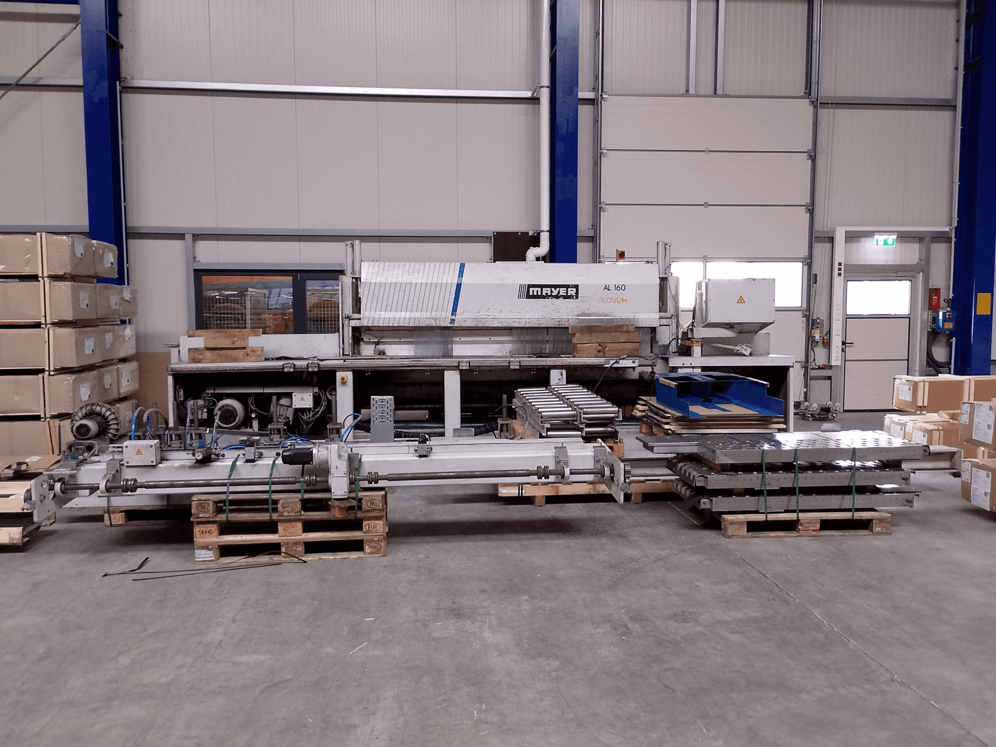 Seccionadora MAYER AL160 en un almacén con palets, mostrando su mesa de corte y los componentes de la máquina, vista frontal.