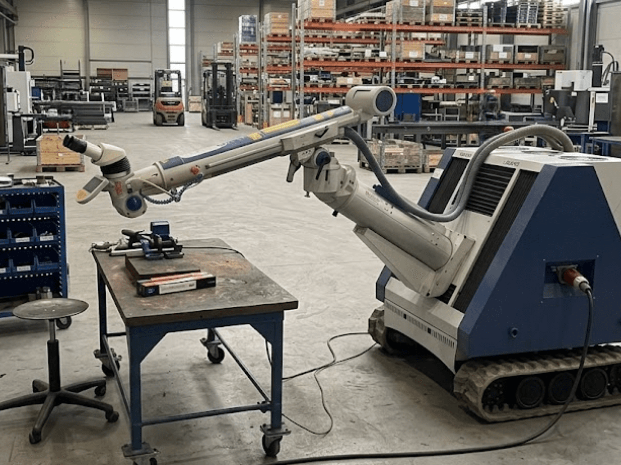 Máquina herramienta ALPHA LASER ALFlak300 M en un taller con brazo robótico; vista frontal que muestra la configuración de precisión en la mesa de trabajo.
