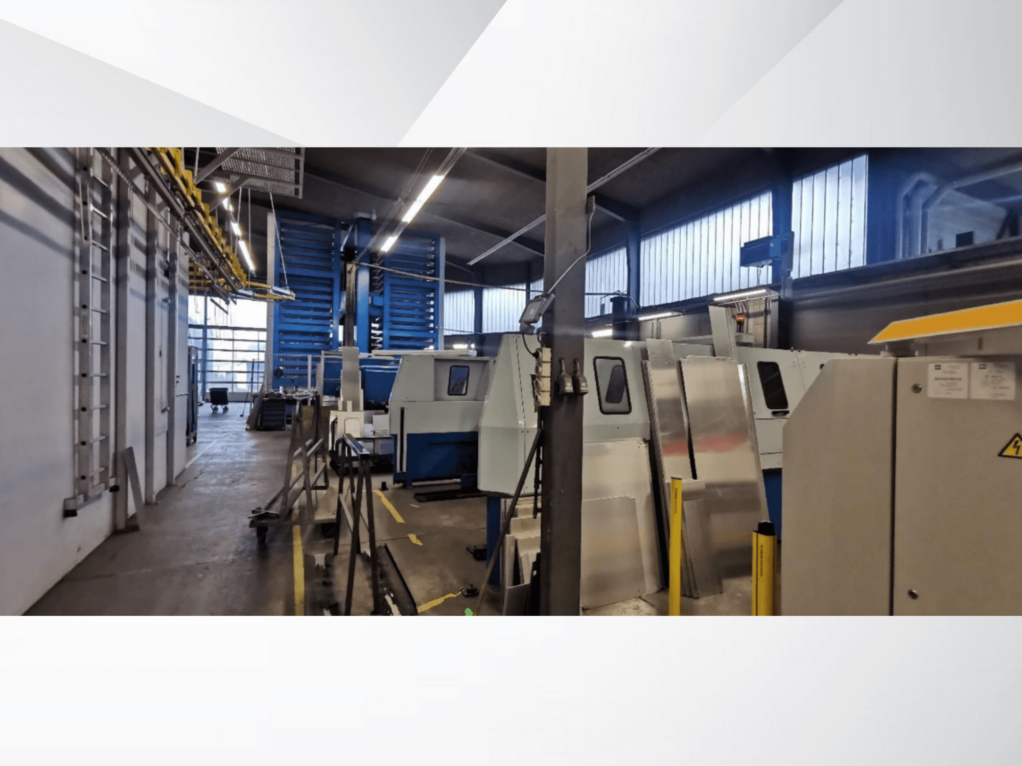Escena de taller industrial con varias máquinas y equipos en una vista lateral, con superficies metálicas y dispositivos de seguridad visibles.