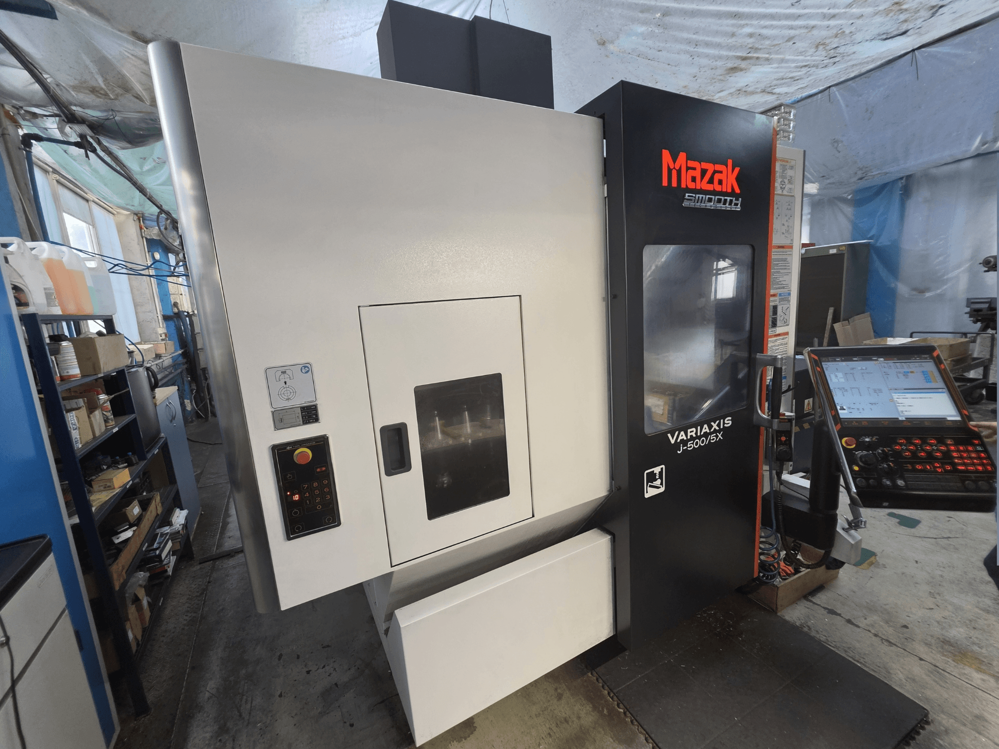 Centro de mecanizado vertical Mazak VARIAXIS J-500/5X visto de frente, con un panel de control y una amplia ventana de visualización del mecanizado.
