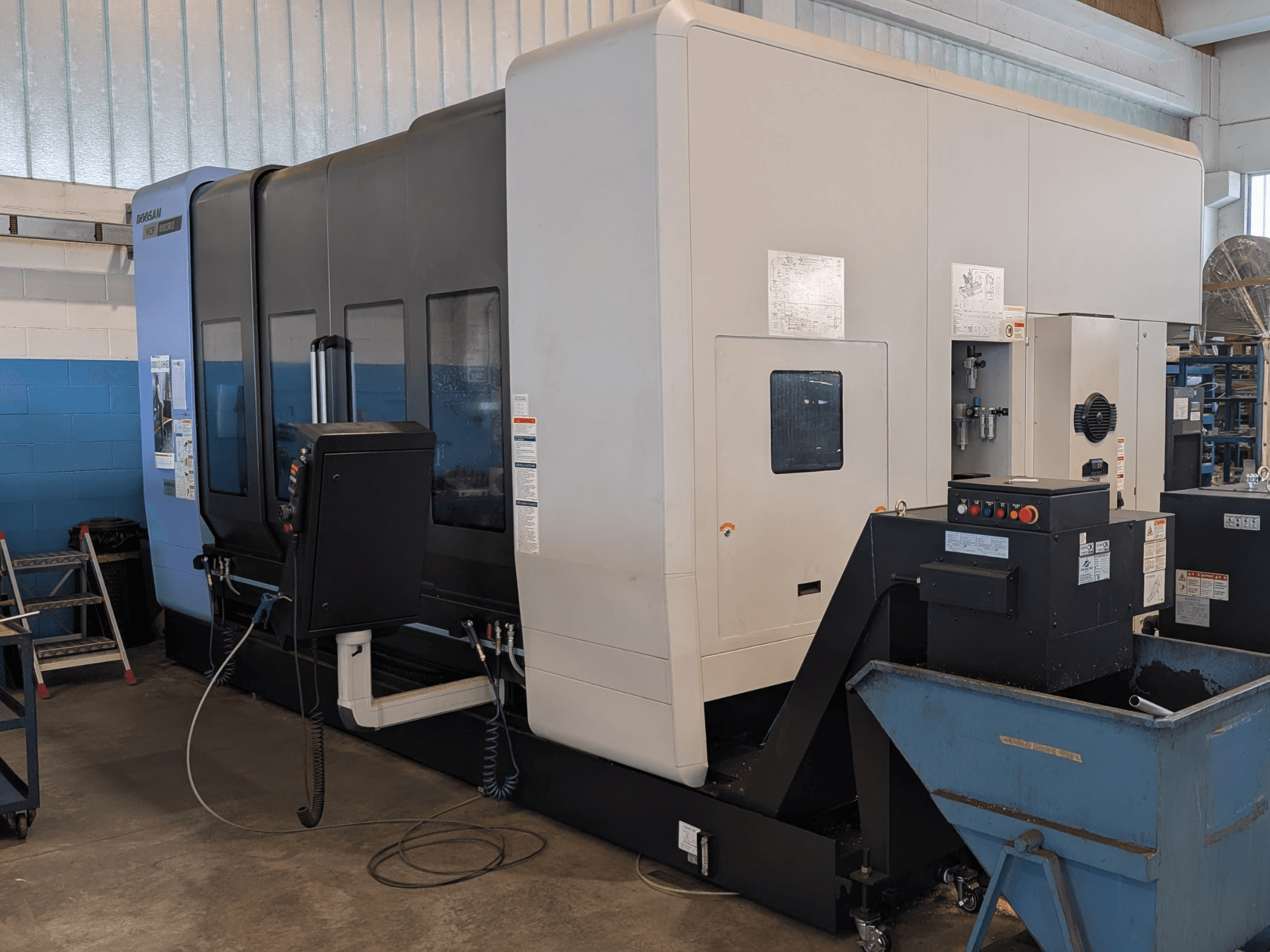 Centro de mecanizado vertical DOOSAN VCF850LSR-II en vista lateral, en el que se aprecian el panel de control, el sistema de refrigeración y su robusta estructura.