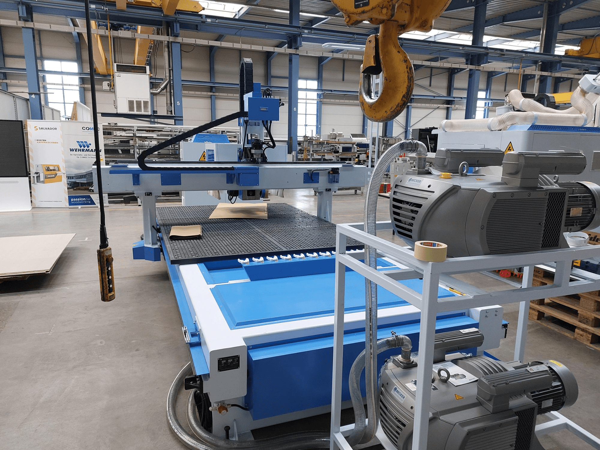 Centro de mecanizado de madera CNC QUICK CNC UA 481, vista frontal en la que se aprecian el panel de control, los motores y la superficie de trabajo con una pieza de madera.