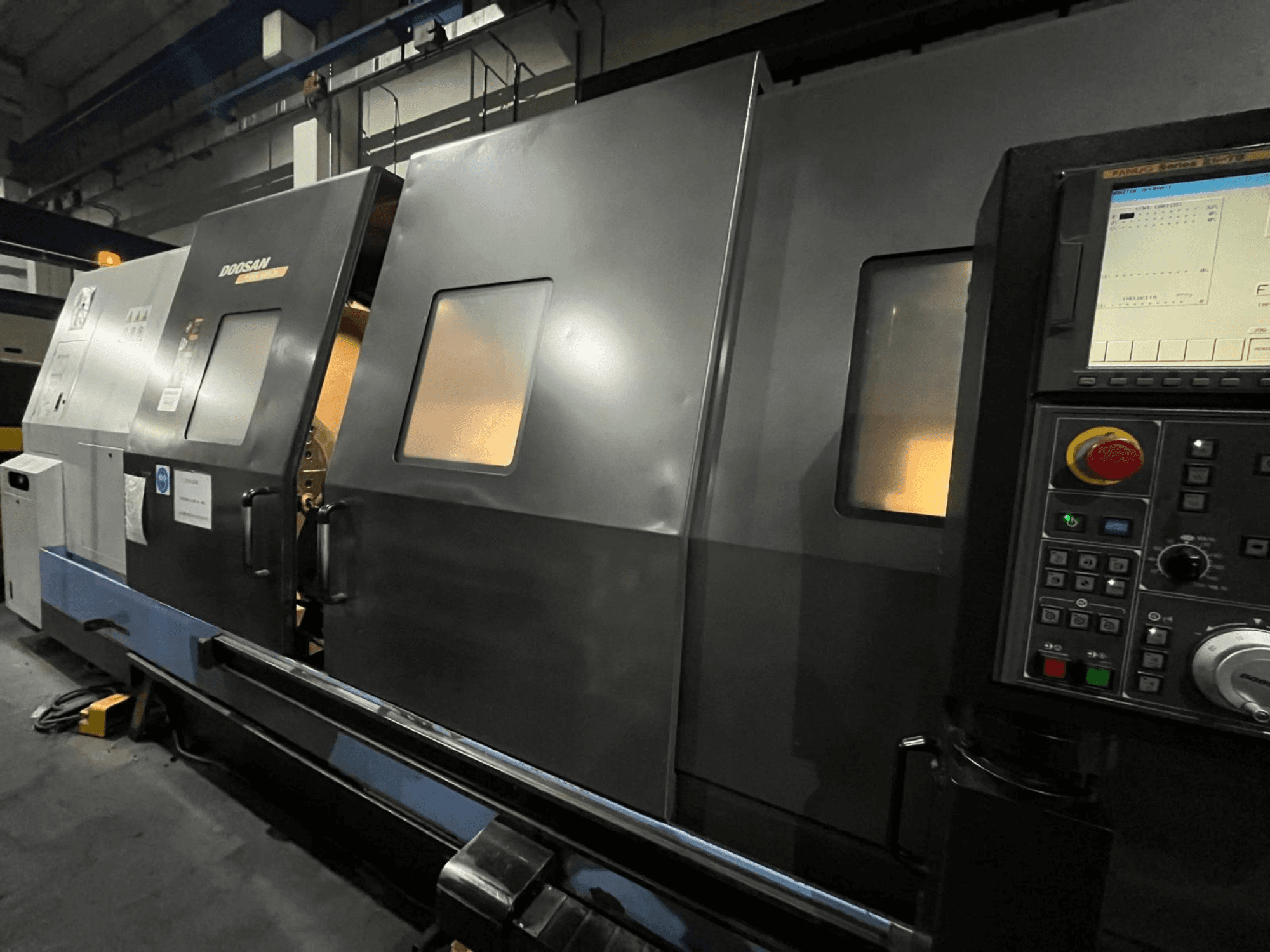 Máquina de torno CNC Doosan en vista frontal, con panel de control e interfaz de operador con pantalla digital visible y botones.