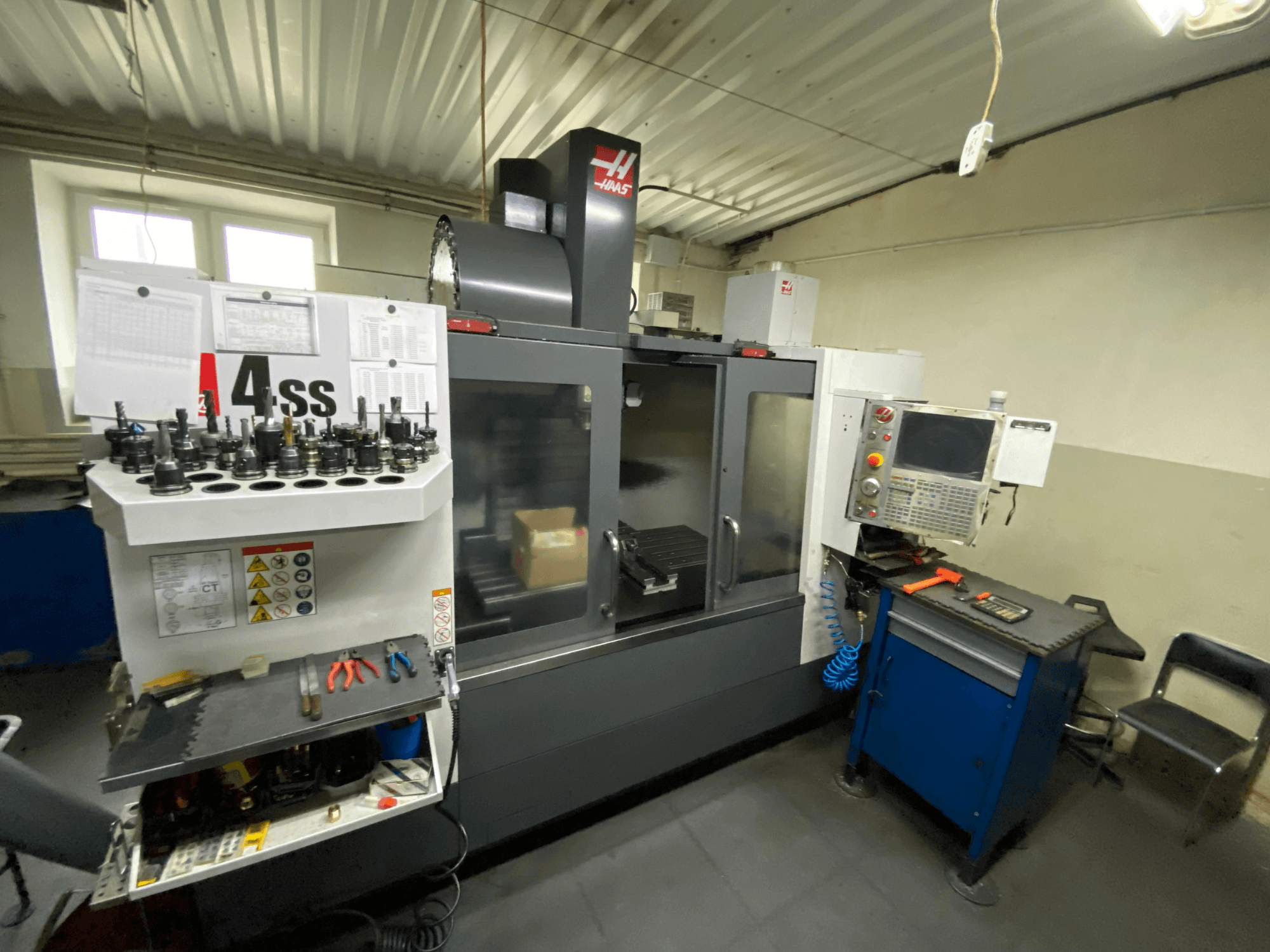 Centro de mecanizado vertical Haas VF-4SS, vista frontal con portaherramientas y panel de control. Se pueden ver las herramientas destacadas y el espacio de trabajo.