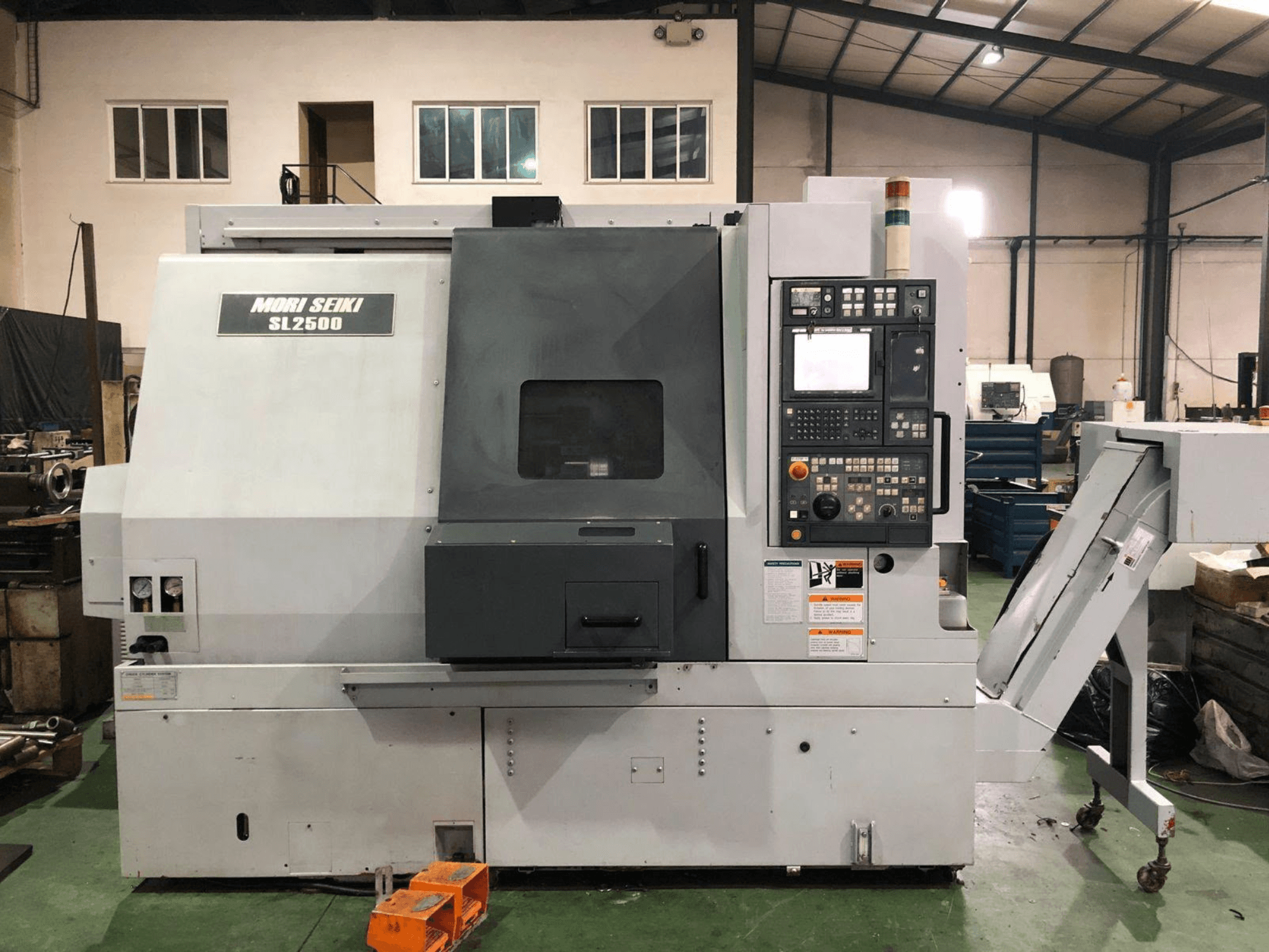 Centro de torneado y fresado DMG Mori Seiki SL 2500 Y, vista lateral en la que se aprecian el panel de control y el transportador de virutas.