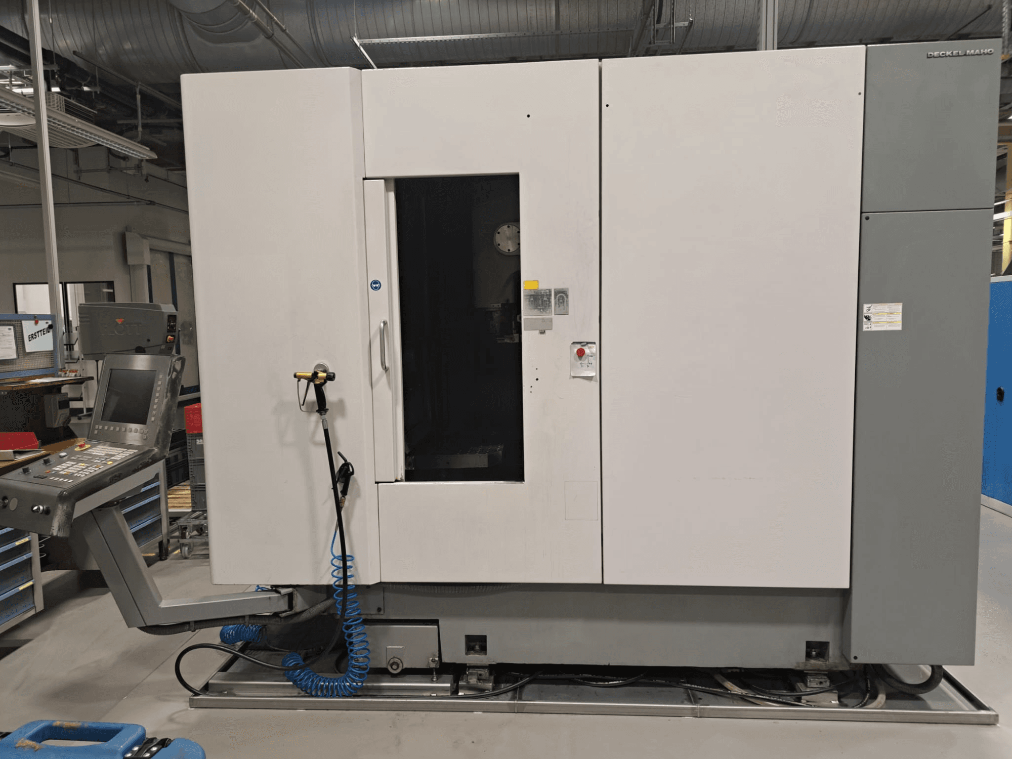 Centro de mecanizado vertical DECKEL MAHO DMP 60V; vista frontal en la que se aprecian el panel de control y el cuerpo principal, con la puerta abierta para facilitar el acceso.