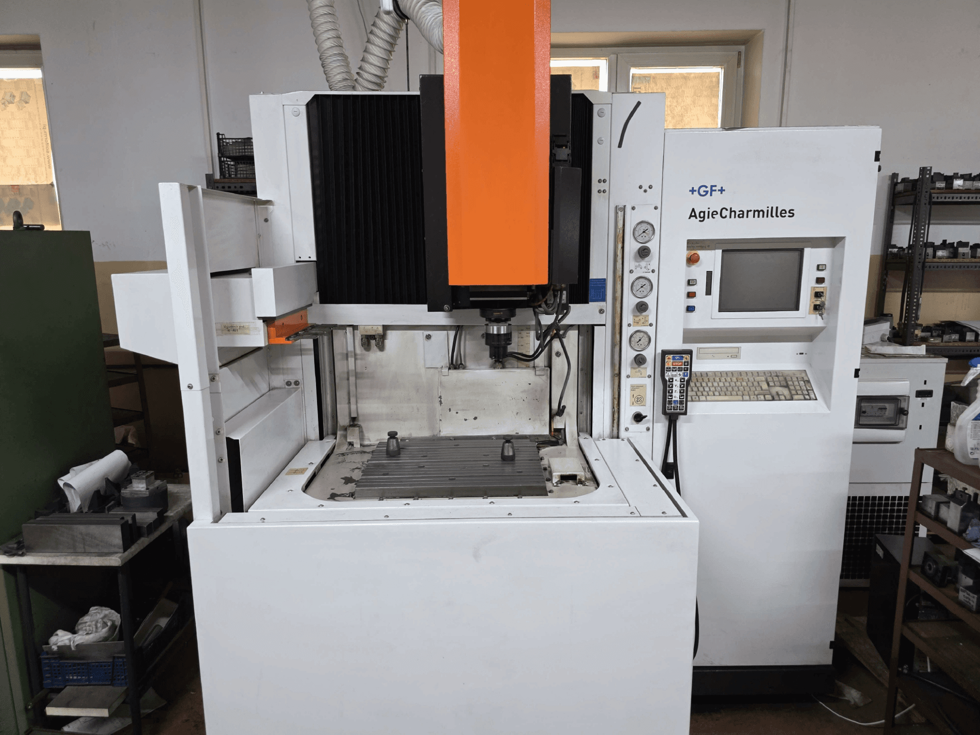 Máquina CNC GF AgieCharmilles, vista frontal con un prominente husillo naranja, panel de control digital y mesa de taladrado montada.