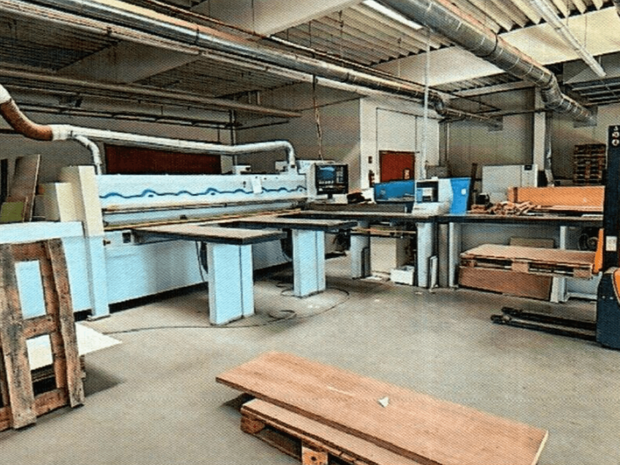 Sierra de paneles HOMAG HPL 11/38/22 en un taller, con una gran mesa de corte y consola de exposición, vista de frente.