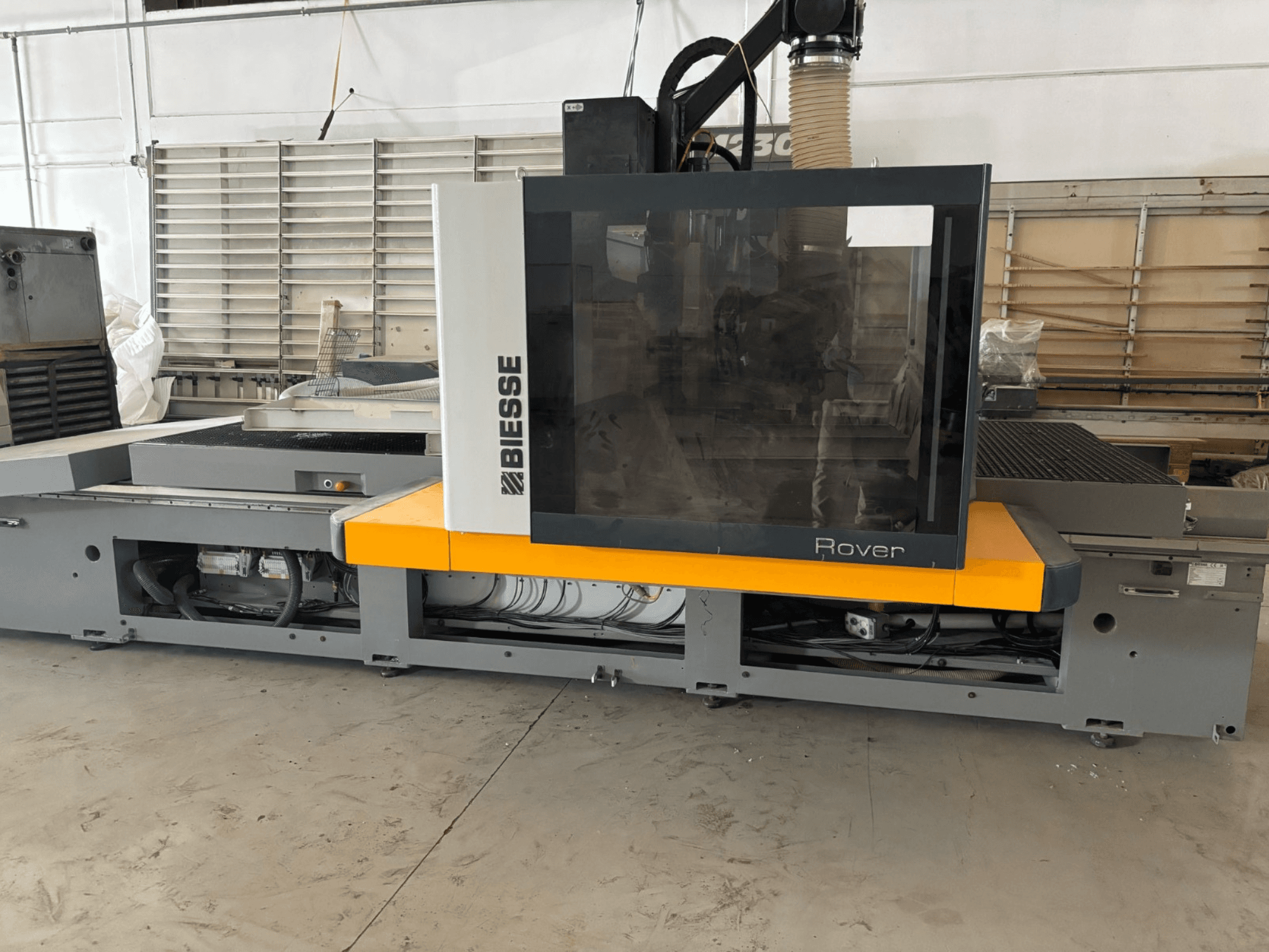 Centro de mecanizado CNC Biesse Rover, vista frontal, con un gran panel de control, detalles en amarillo y componentes mecánicos a la vista.
